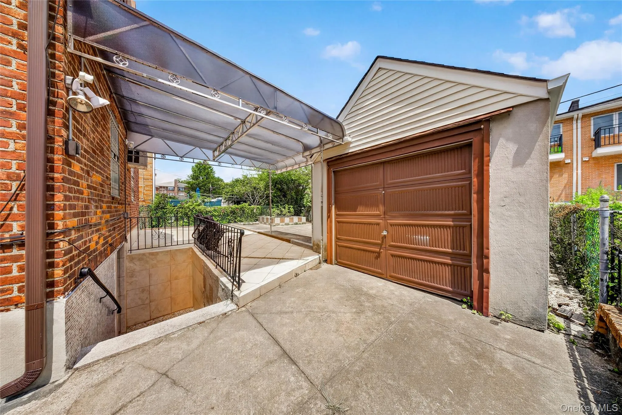 Attached garage with a brown panel door, concrete driveway, and a covered entry leading to a lower-level entrance Attached garage with a brown panel door, concrete driveway, and a covered entry leading to a lower-level entrance