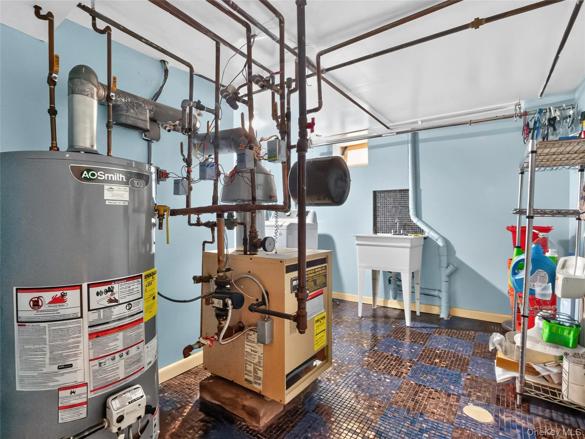 Utility room featuring a water heater, boiler, laundry sink, and durable tiled flooring Utility room featuring a water heater, boiler, laundry sink, and durable tiled flooring