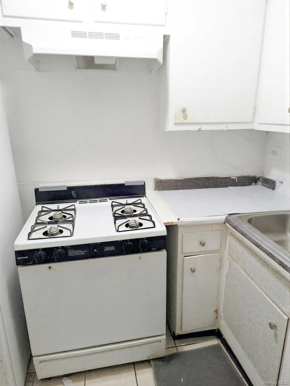 White gas range with four burners, accompanied by a matching range hood White gas range with four burners, accompanied by a matching range hood