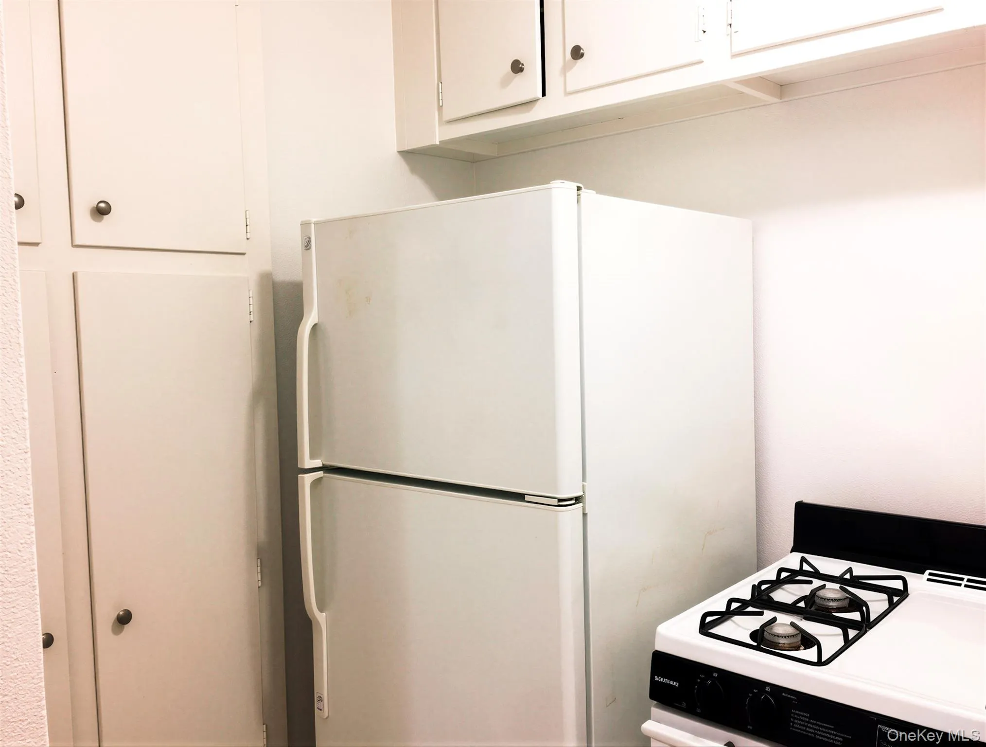 White top-freezer refrigerator with a gas range featuring four burners White top-freezer refrigerator with a gas range featuring four burners