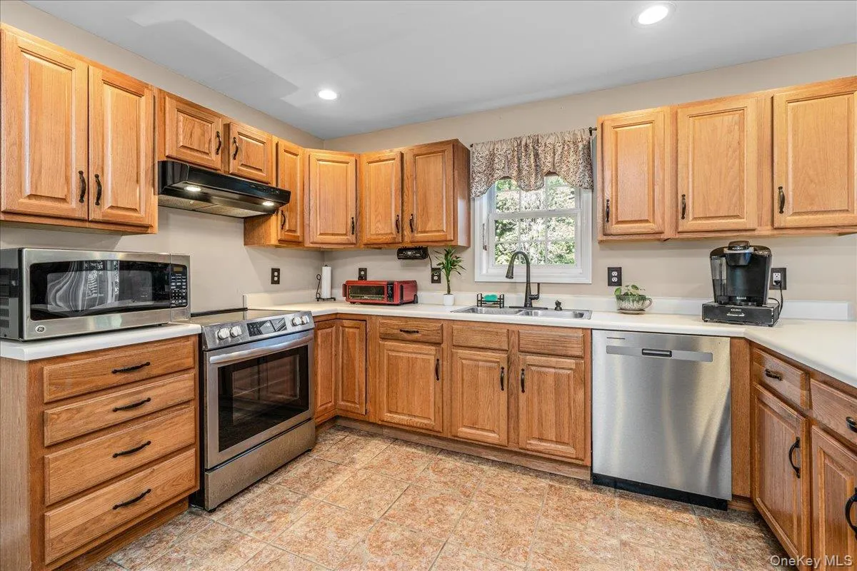Kitchen featuring wood cabinetry with black hardware, light-toned countertops, and tile flooring. Kitchen featuring wood cabinetry with black hardware, light-toned countertops, and tile flooring.