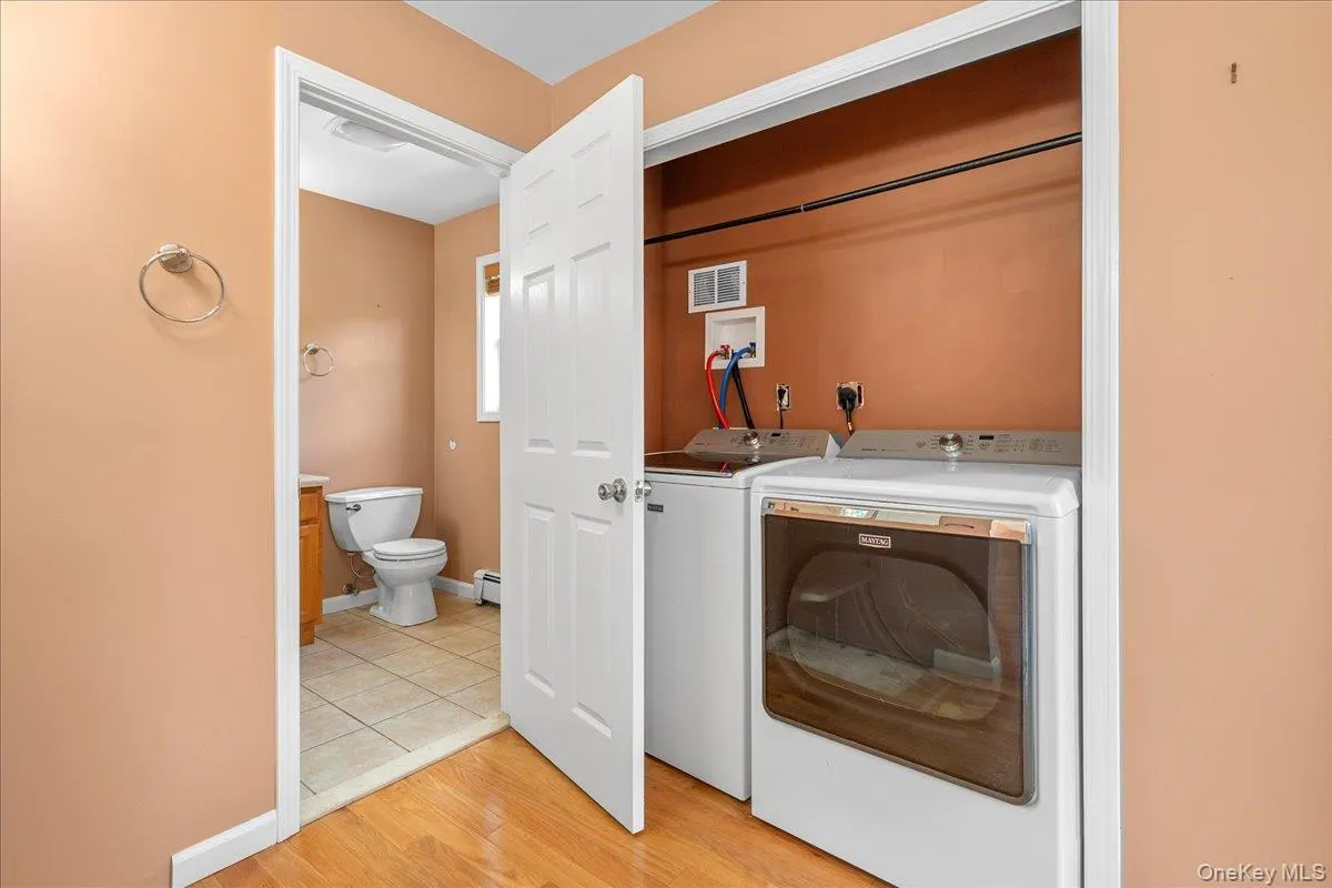 2nd Floor laundry closet featuring washer and dryer, with a full bathroom with tile flooring and a window visible beyond 2nd Floor laundry closet featuring washer and dryer, with a full bathroom with tile flooring and a window visible beyond