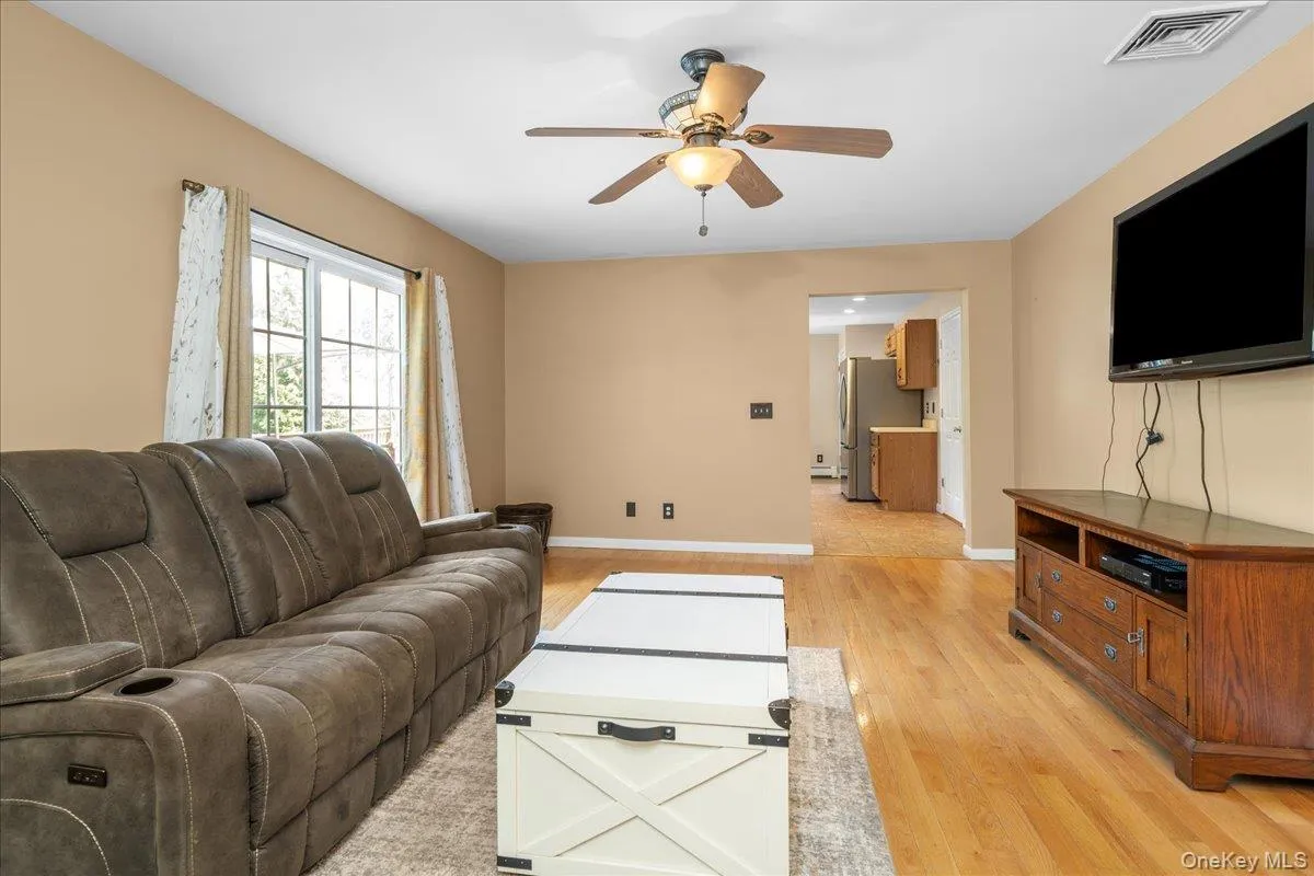 Hardwood flooring throughout the main living area, featuring a ceiling fan with integrated lighting and a window with natural light. Hardwood flooring throughout the main living area, featuring a ceiling fan with integrated lighting and a window with natural light.