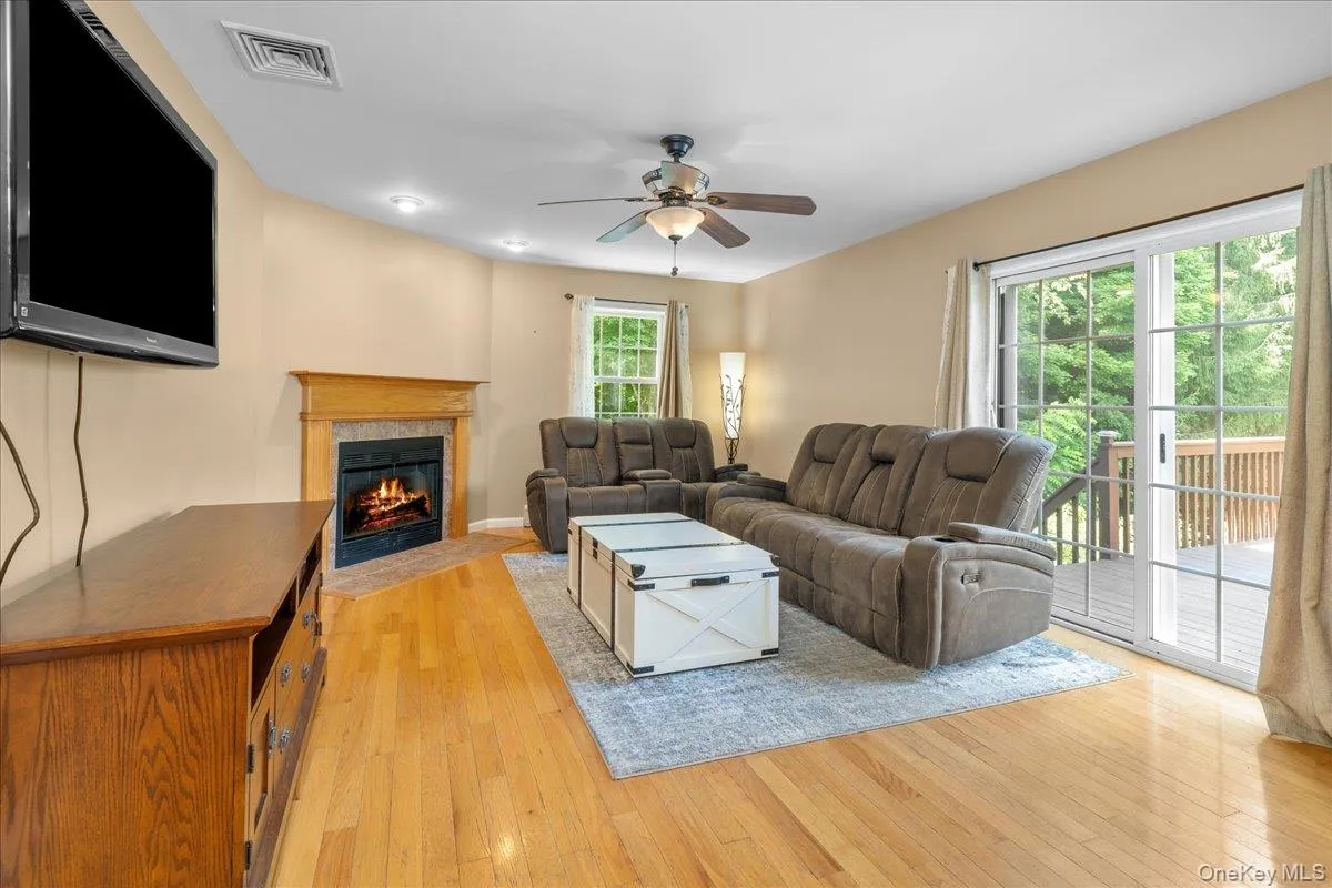 Living area featuring wood-finish flooring, a corner fireplace with a wood mantle, and recessed lighting. Living area featuring wood-finish flooring, a corner fireplace with a wood mantle, and recessed lighting.