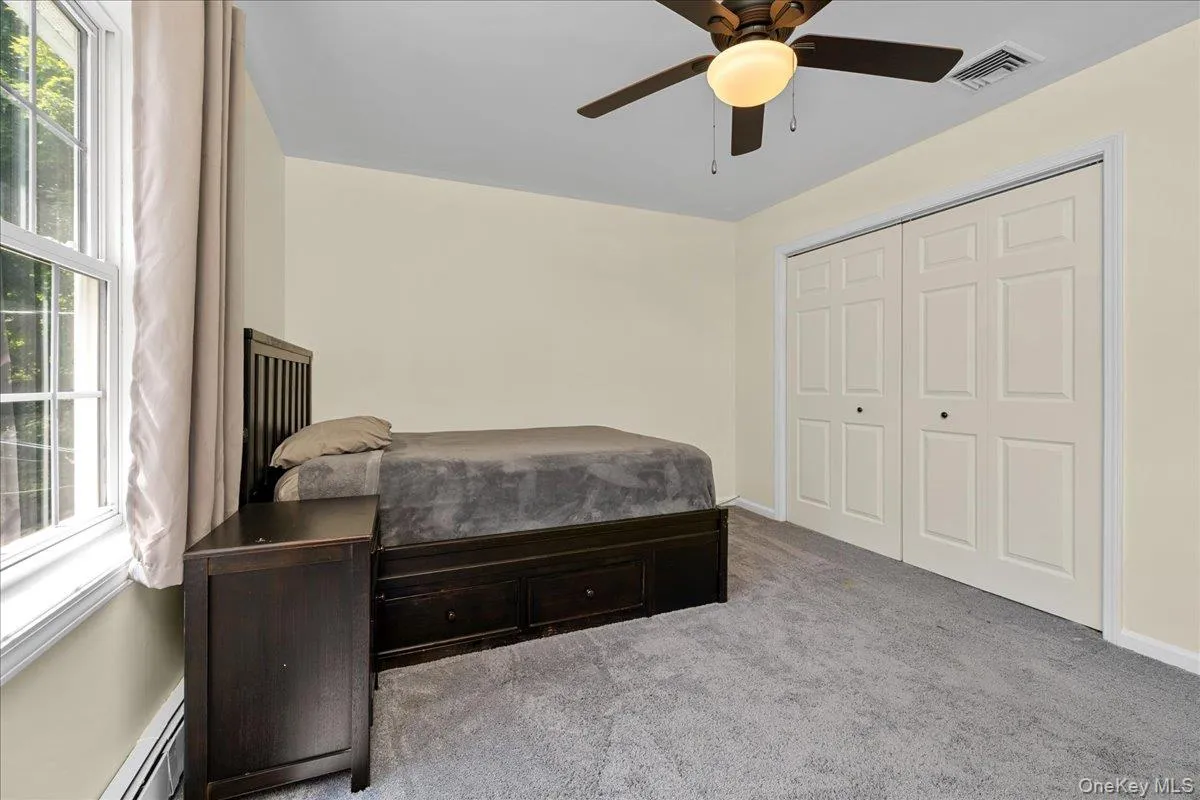 Carpeted rbedoom featuring a ceiling fan, a window with natural light, and bi-fold closet doors Carpeted rbedoom featuring a ceiling fan, a window with natural light, and bi-fold closet doors