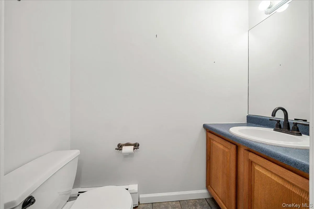 Bathroom featuring a single vanity with wood-finish cabinetry, a blue/green countertop, and a white integrated sink Bathroom featuring a single vanity with wood-finish cabinetry, a blue/green countertop, and a white integrated sink
