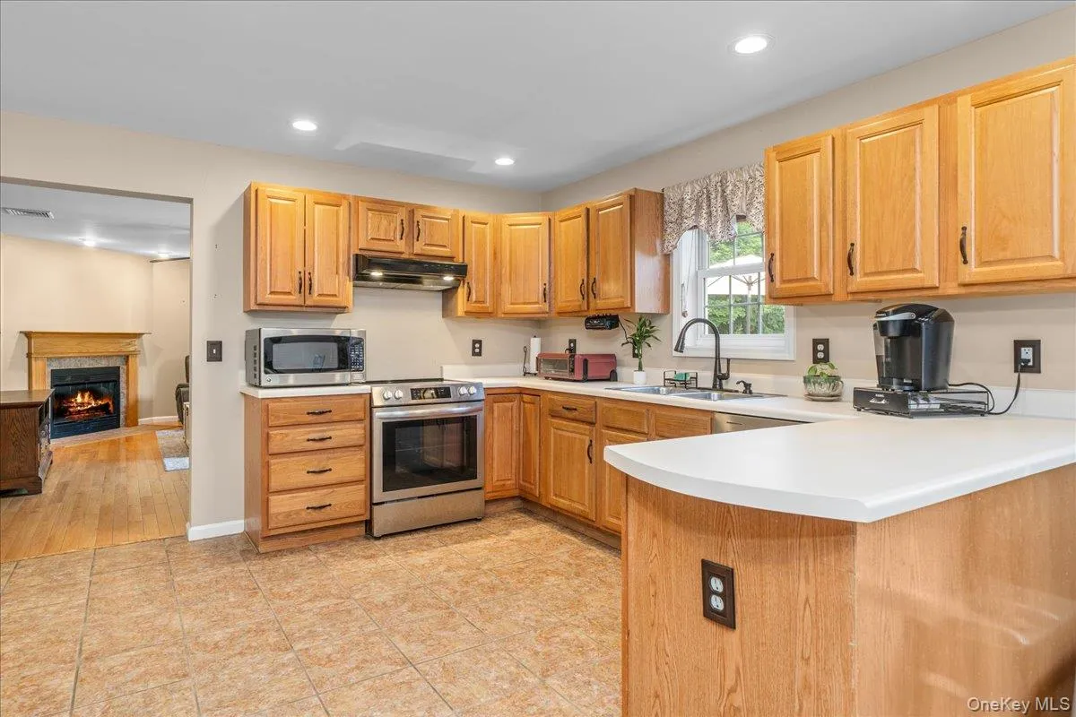Kitchen featuring wood cabinetry, light-toned countertops, and stainless steel appliances. Kitchen featuring wood cabinetry, light-toned countertops, and stainless steel appliances.