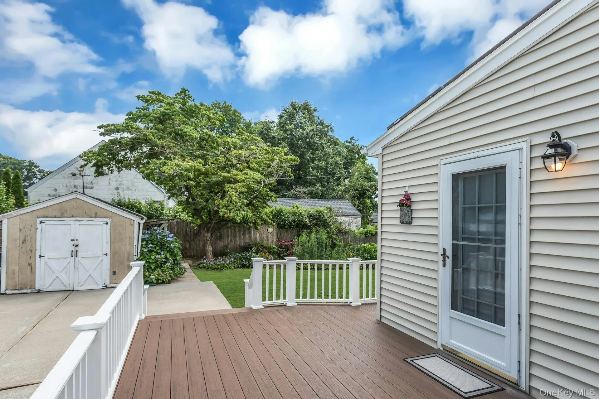Expansive outdoor deck featuring wood-finish decking and white railings Expansive outdoor deck featuring wood-finish decking and white railings