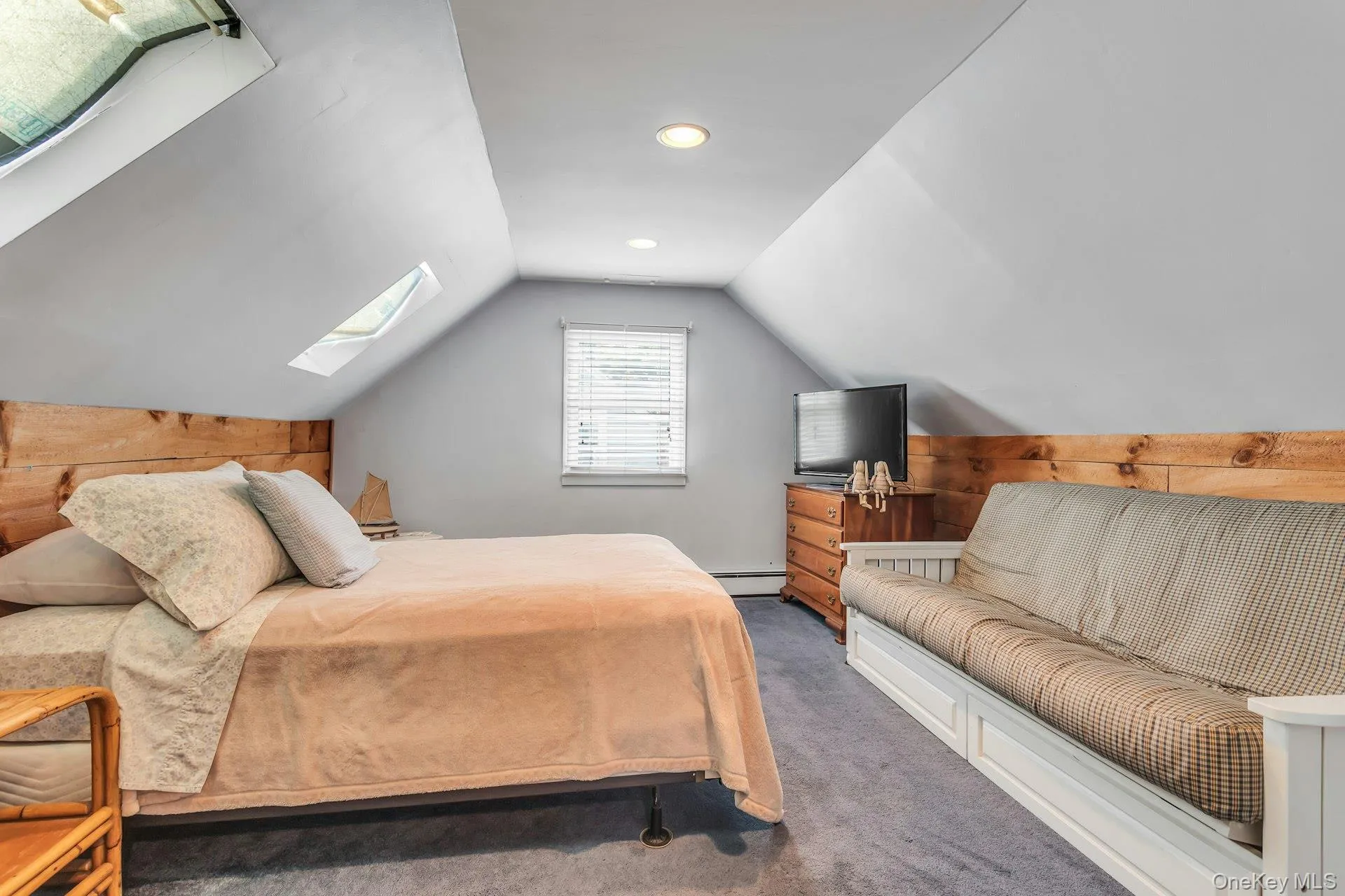 Attic space featuring vaulted ceilings, two skylights, recessed lighting, and a wood-paneled accent wall Attic space featuring vaulted ceilings, two skylights, recessed lighting, and a wood-paneled accent wall