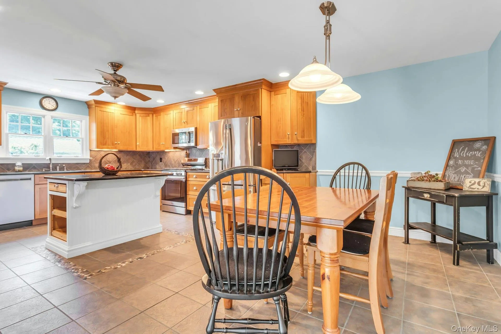 Kitchen featuring warm-toned wood cabinetry, stainless steel appliances, and a central island with a contrasting countertop Kitchen featuring warm-toned wood cabinetry, stainless steel appliances, and a central island with a contrasting countertop