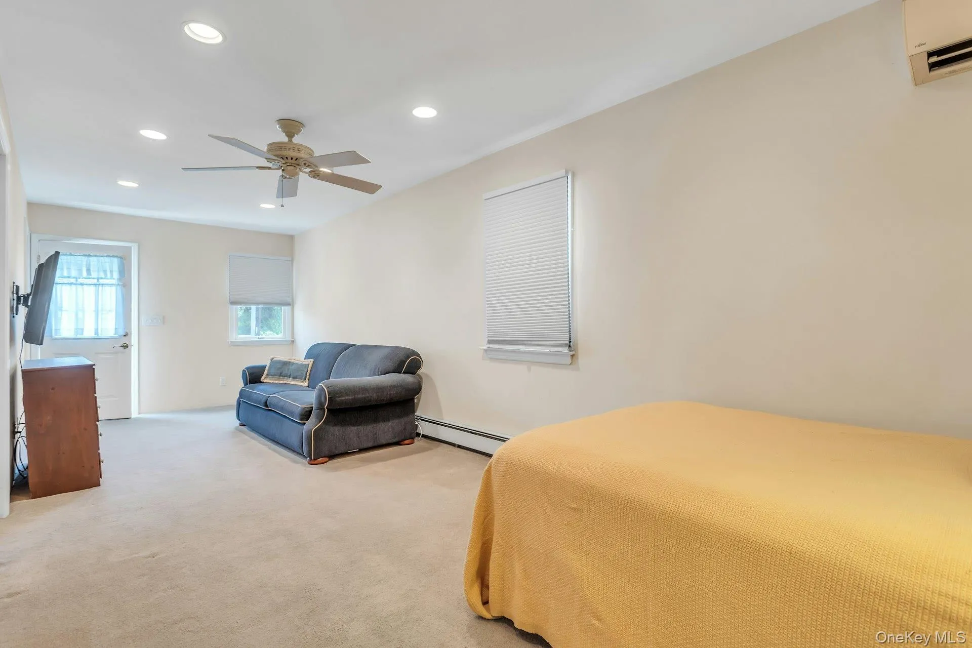 Carpeted room featuring recessed lighting, a ceiling fan, a wall-mounted AC unit, and a window with blinds Carpeted room featuring recessed lighting, a ceiling fan, a wall-mounted AC unit, and a window with blinds