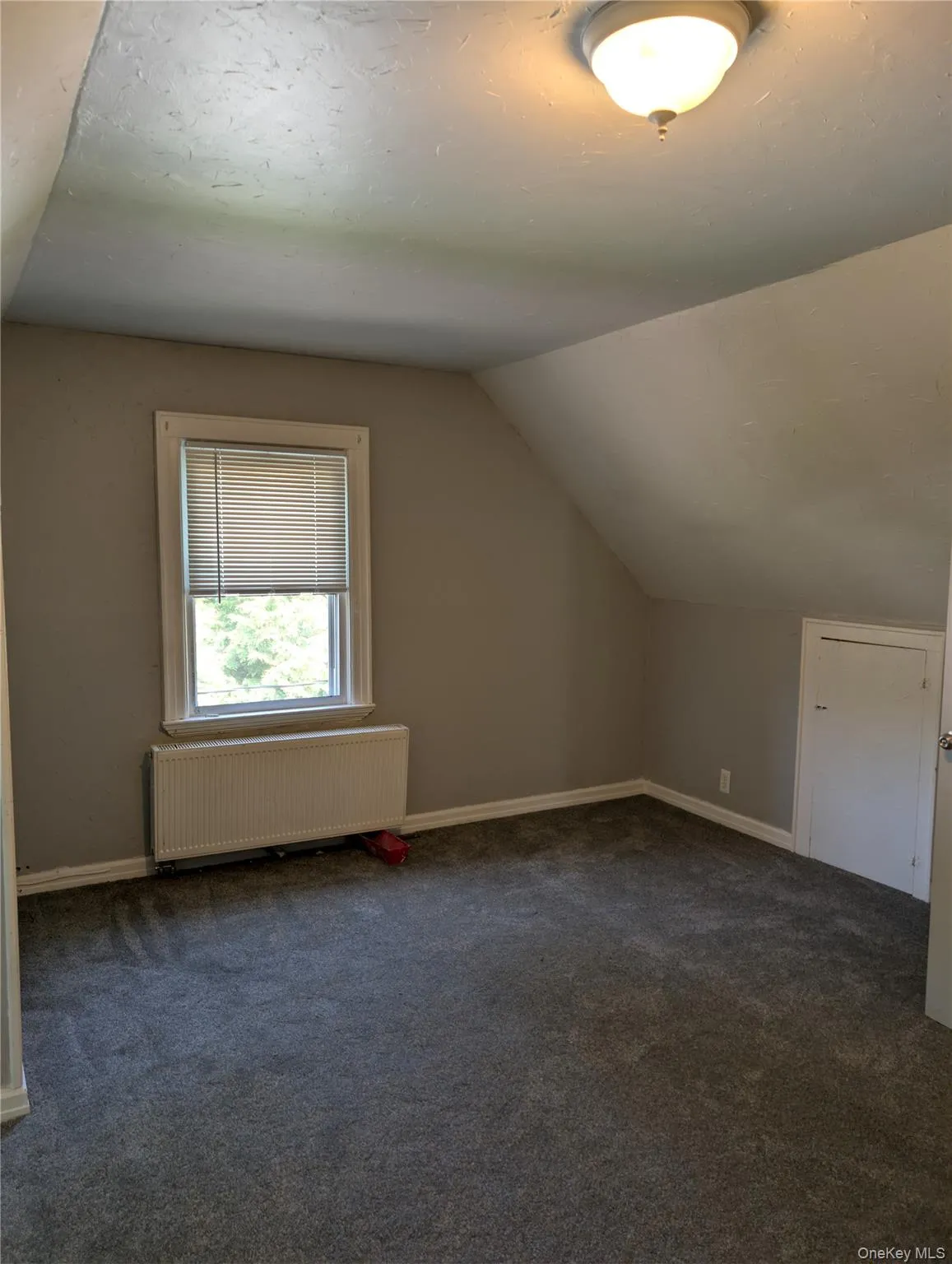 Newly carpeted bedroom with a window features blinds, a radiator below, 2 closets, dual windows and a built-in eve storage door Newly carpeted bedroom with a window features blinds, a radiator below, 2 closets, dual windows and a built-in eve storage door