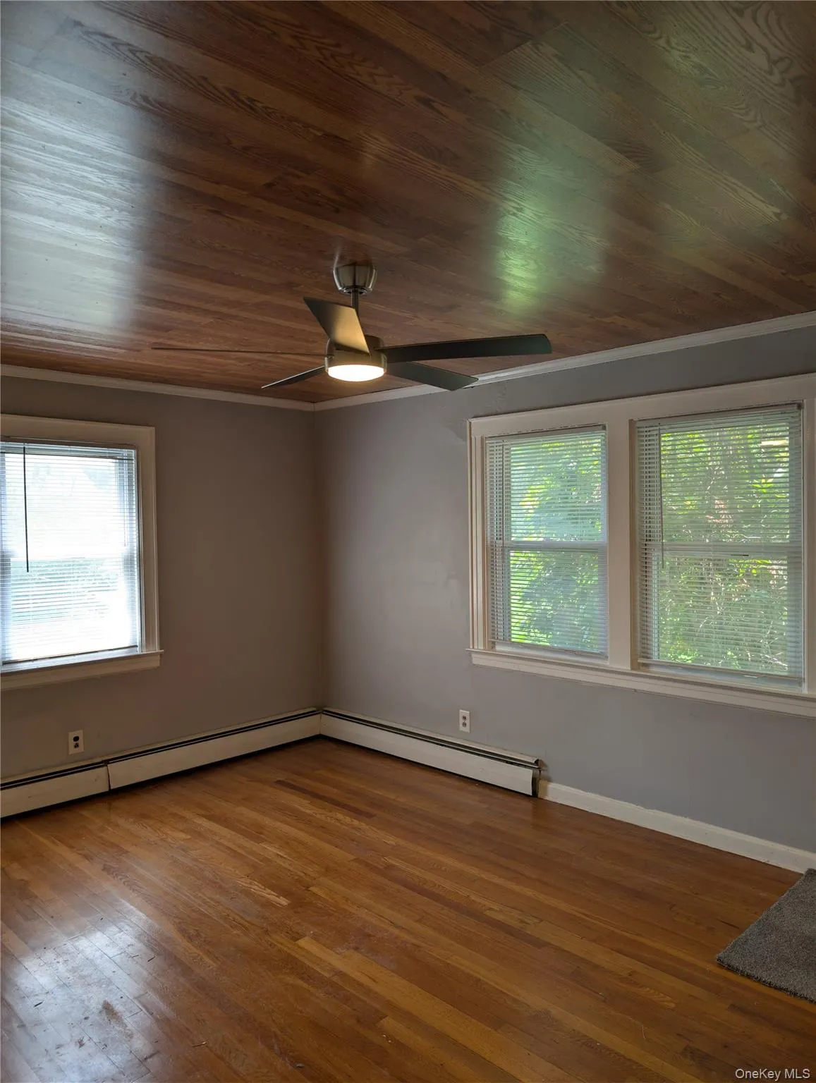 Den features wood-finish flooring, light grey walls, and a wood-finish ceiling with a modern ceiling fan Den features wood-finish flooring, light grey walls, and a wood-finish ceiling with a modern ceiling fan