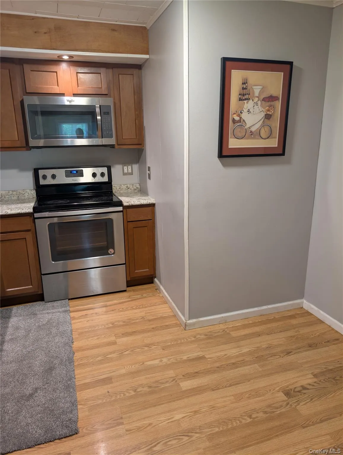 Kitchen space features wood-finish flooring and light gray walls, stainless steel appliances and eating area Kitchen space features wood-finish flooring and light gray walls, stainless steel appliances and eating area