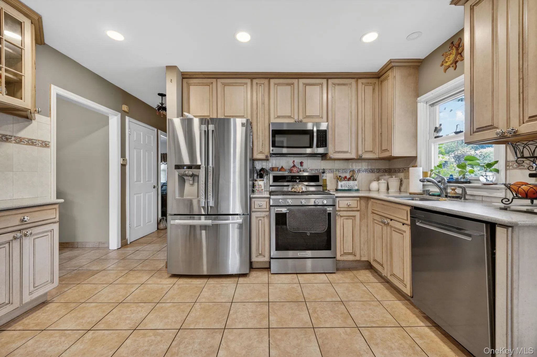 Kitchen featuring light-toned cabinetry, stainless steel appliances, tile flooring, and recessed lighting Kitchen featuring light-toned cabinetry, stainless steel appliances, tile flooring, and recessed lighting
