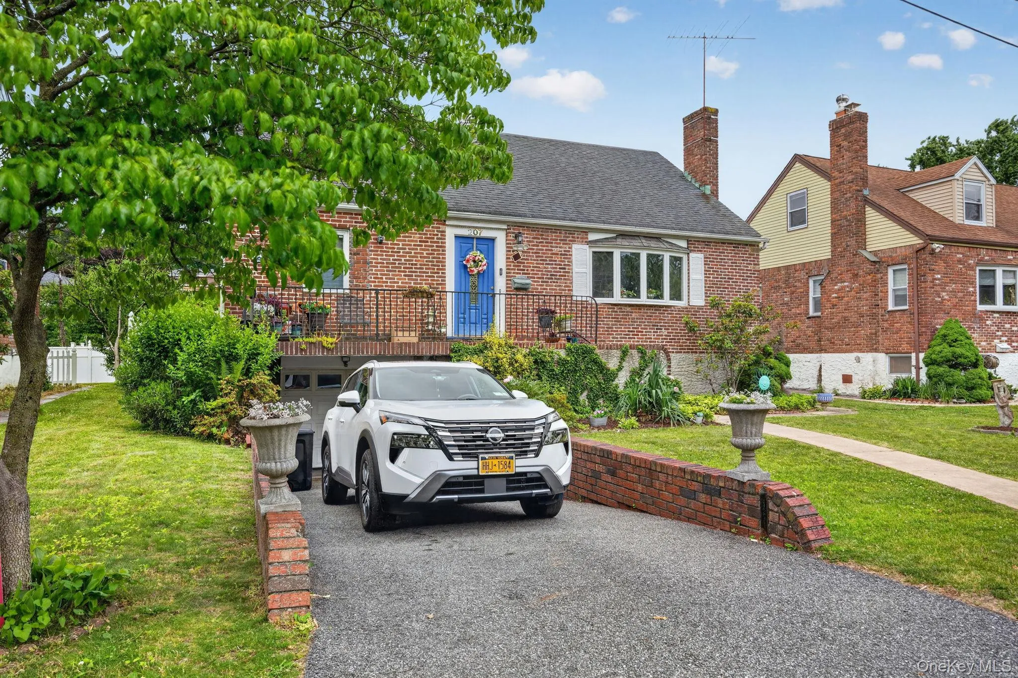 Brick residence featuring a charcoal shingle roof, a prominent bay window with shutters, and a front porch with an ornate metal railing Brick residence featuring a charcoal shingle roof, a prominent bay window with shutters, and a front porch with an ornate metal railing