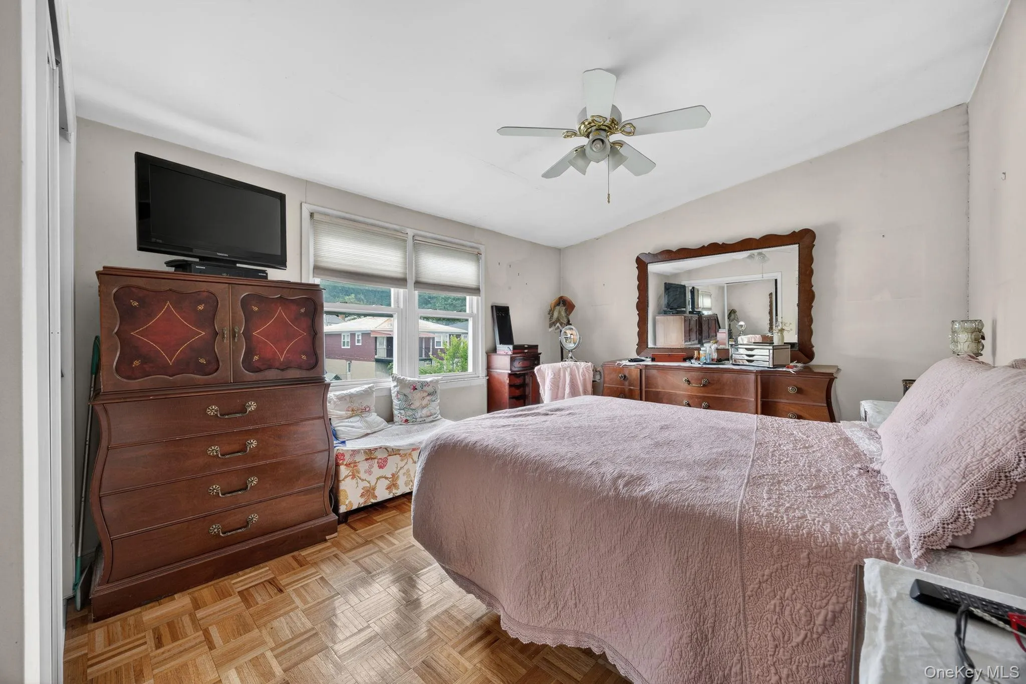 Room featuring wood-finish parquet flooring, multiple windows with blinds, and an overhead ceiling fan with lighting Room featuring wood-finish parquet flooring, multiple windows with blinds, and an overhead ceiling fan with lighting