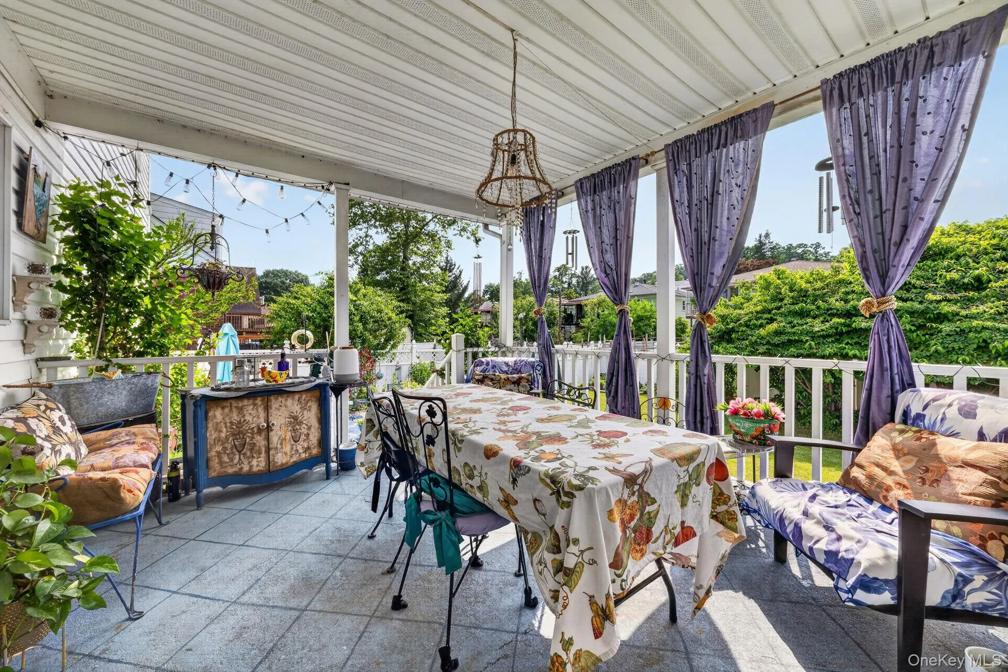 Spacious covered porch featuring tiled flooring, a slatted ceiling, and white railing Spacious covered porch featuring tiled flooring, a slatted ceiling, and white railing