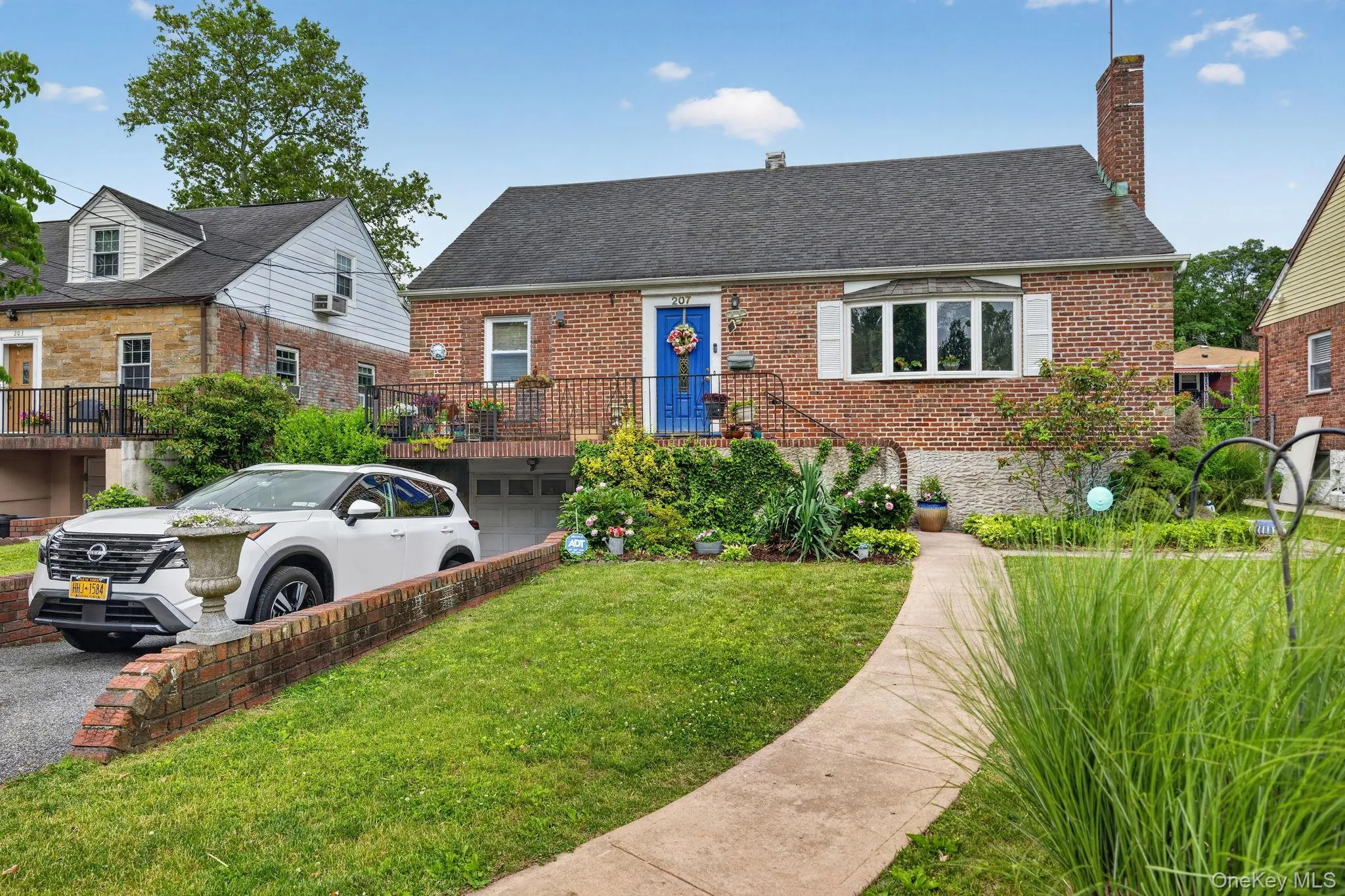 Brick facade home featuring a prominent bay window with white shutters, a vibrant blue entry door, and a brick chimney Brick facade home featuring a prominent bay window with white shutters, a vibrant blue entry door, and a brick chimney