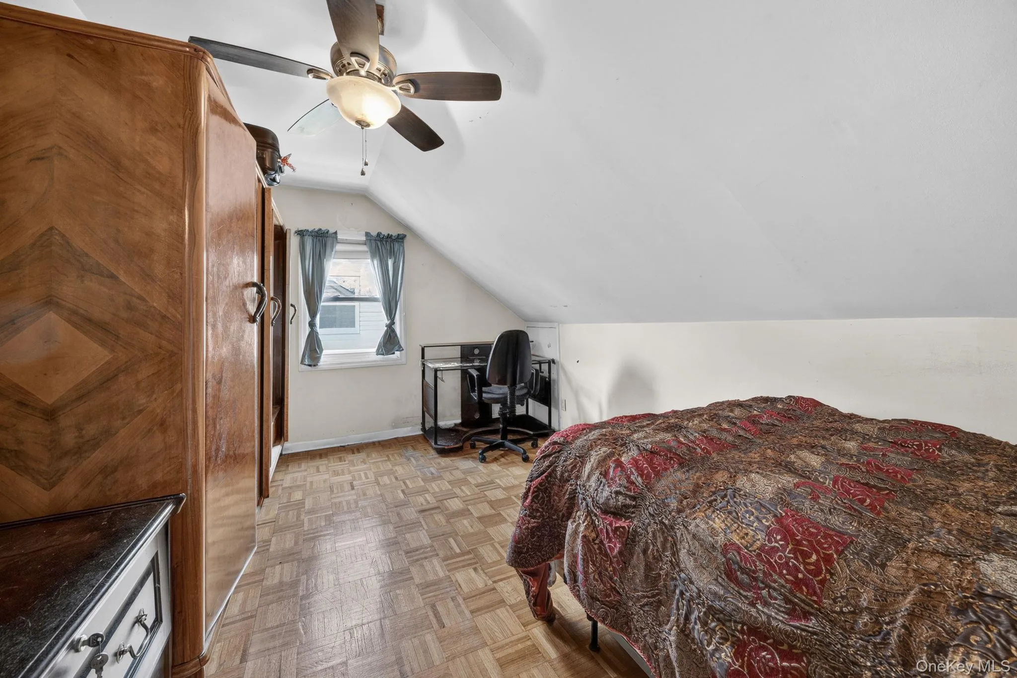 Room featuring a sloped ceiling, wood-finish flooring, a window, and a ceiling fan with integrated lighting Room featuring a sloped ceiling, wood-finish flooring, a window, and a ceiling fan with integrated lighting