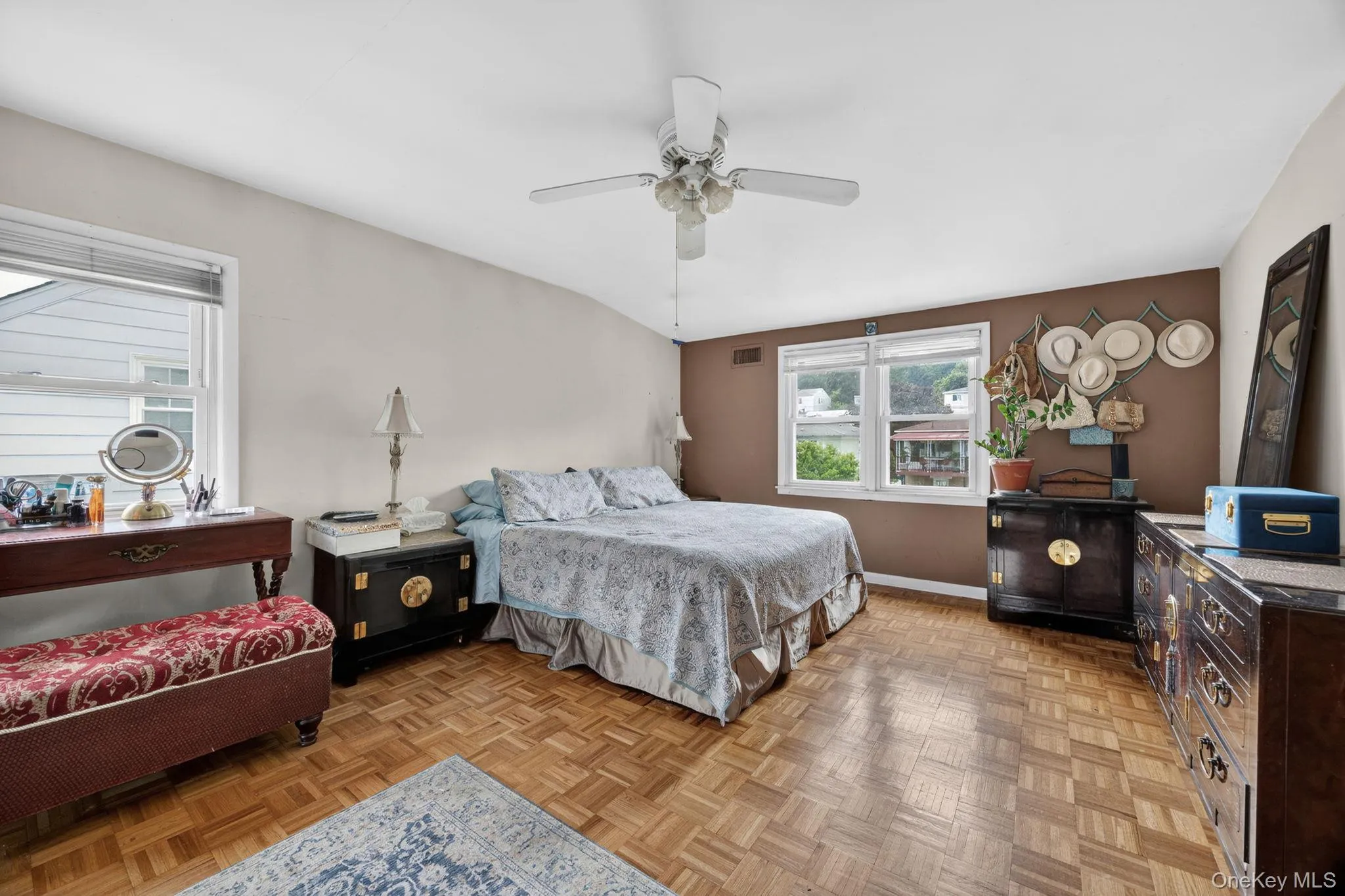 Spacious room featuring parquet wood-finish flooring, a ceiling fan, and multiple windows Spacious room featuring parquet wood-finish flooring, a ceiling fan, and multiple windows
