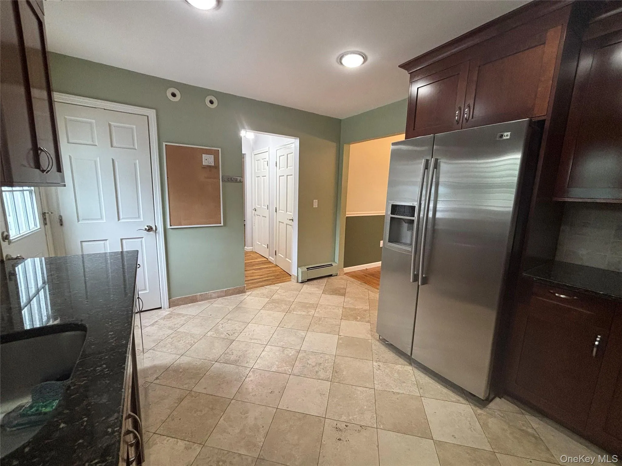 Kitchen featuring diagonal tile flooring, dark wood cabinetry, a stainless steel refrigerator, dark granite countertops, and recessed lighting Kitchen featuring diagonal tile flooring, dark wood cabinetry, a stainless steel refrigerator, dark granite countertops, and recessed lighting