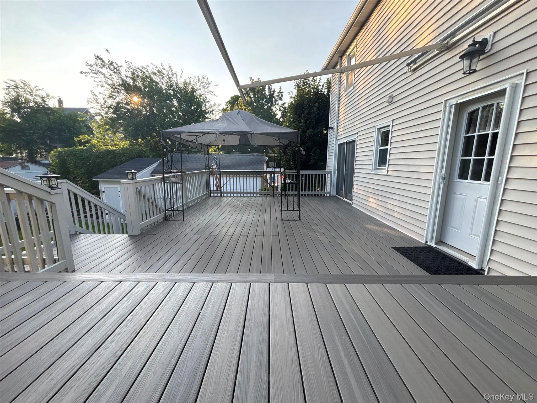 Multi-level deck featuring composite decking, white railings with integrated lighting, and direct access to the interior via a white paneled door Multi-level deck featuring composite decking, white railings with integrated lighting, and direct access to the interior via a white paneled door