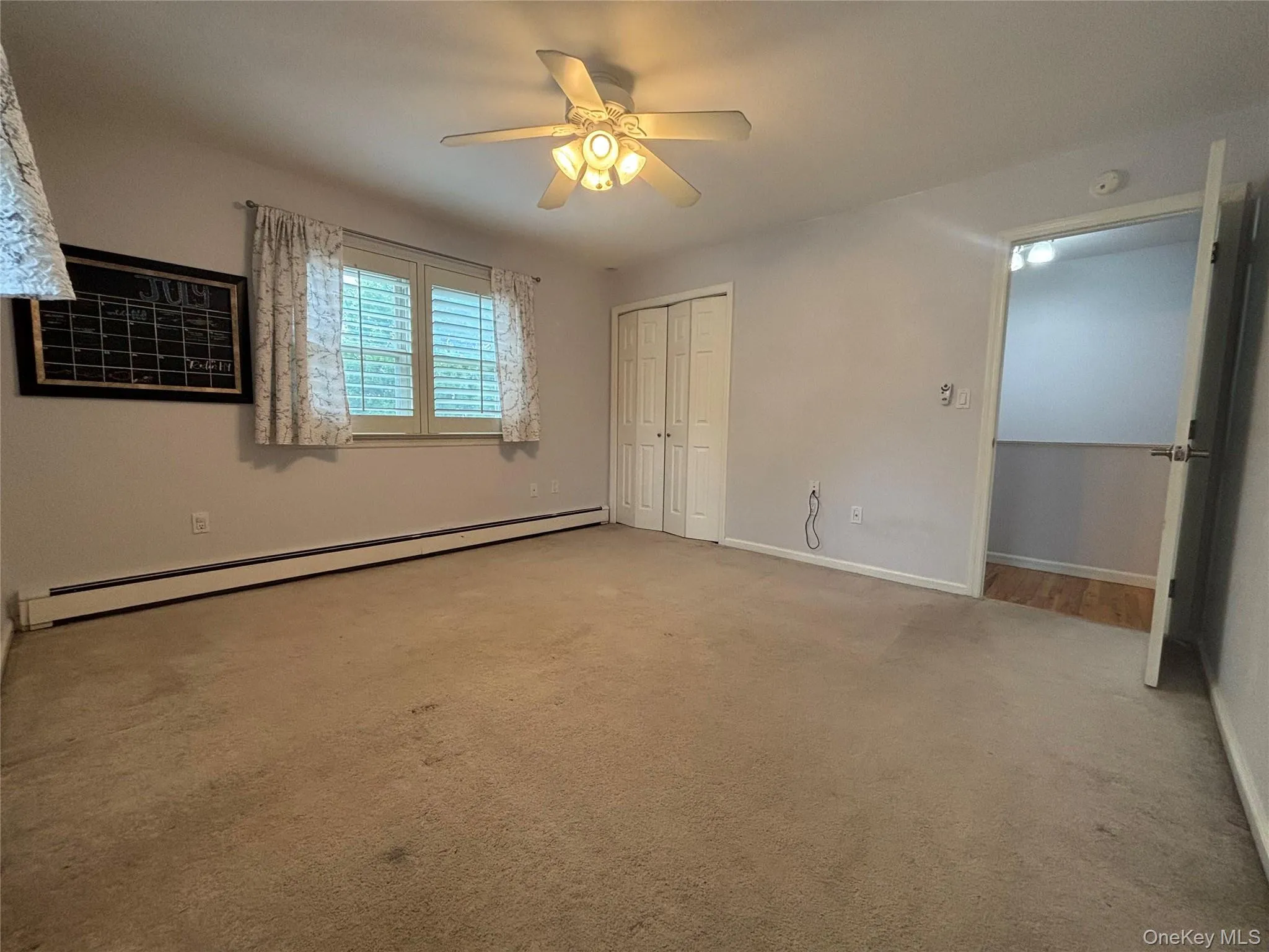 Carpeted interior space featuring a ceiling fan with integrated lighting, a window with louvered blinds, and baseboard heating Carpeted interior space featuring a ceiling fan with integrated lighting, a window with louvered blinds, and baseboard heating