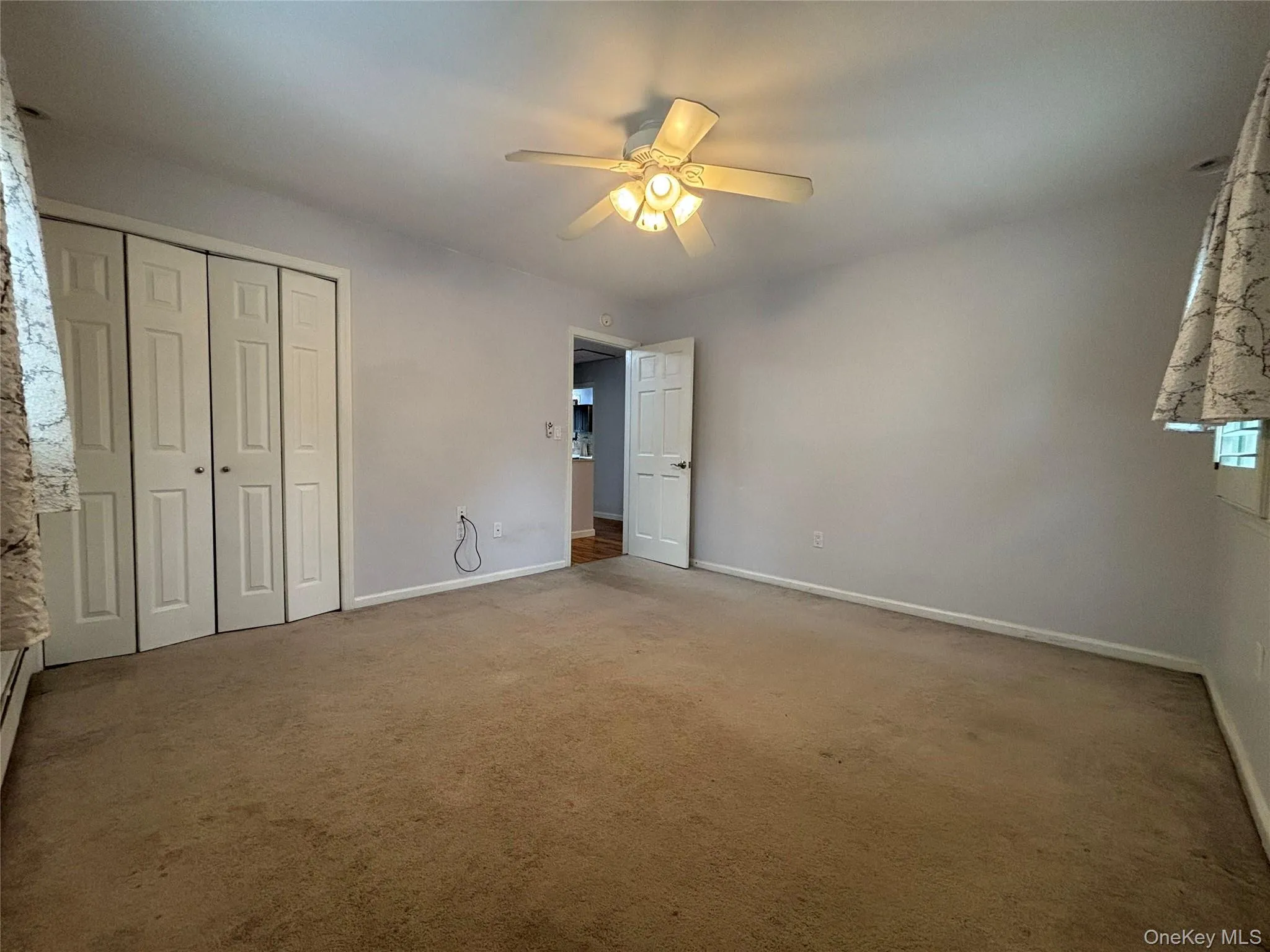Room featuring light-colored walls and tan carpeting Room featuring light-colored walls and tan carpeting
