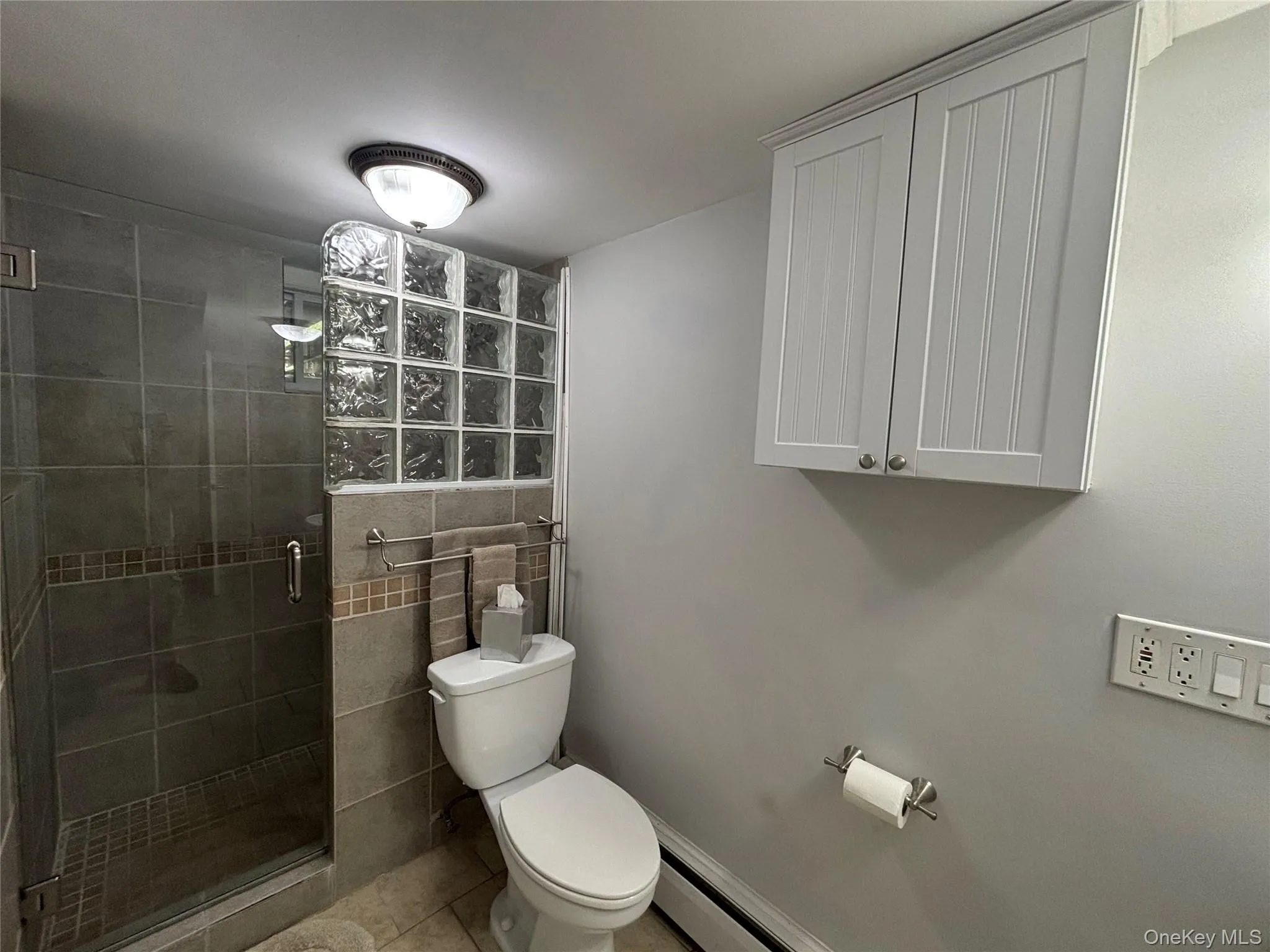 Shower enclosure featuring glass blocks and full-height tiling with a decorative accent band Shower enclosure featuring glass blocks and full-height tiling with a decorative accent band