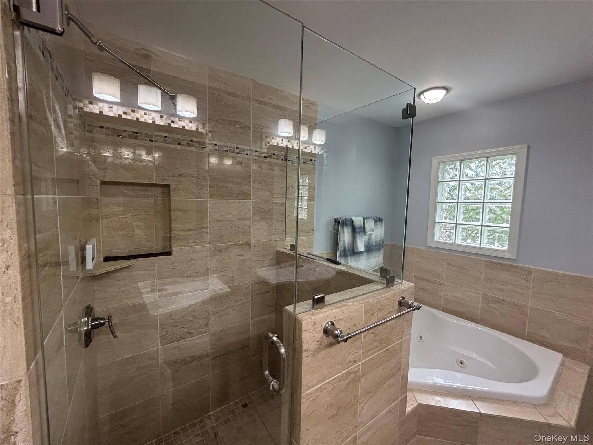 Glass-enclosed shower with full-height tile surround, built-in niche, and integrated bench seating Glass-enclosed shower with full-height tile surround, built-in niche, and integrated bench seating