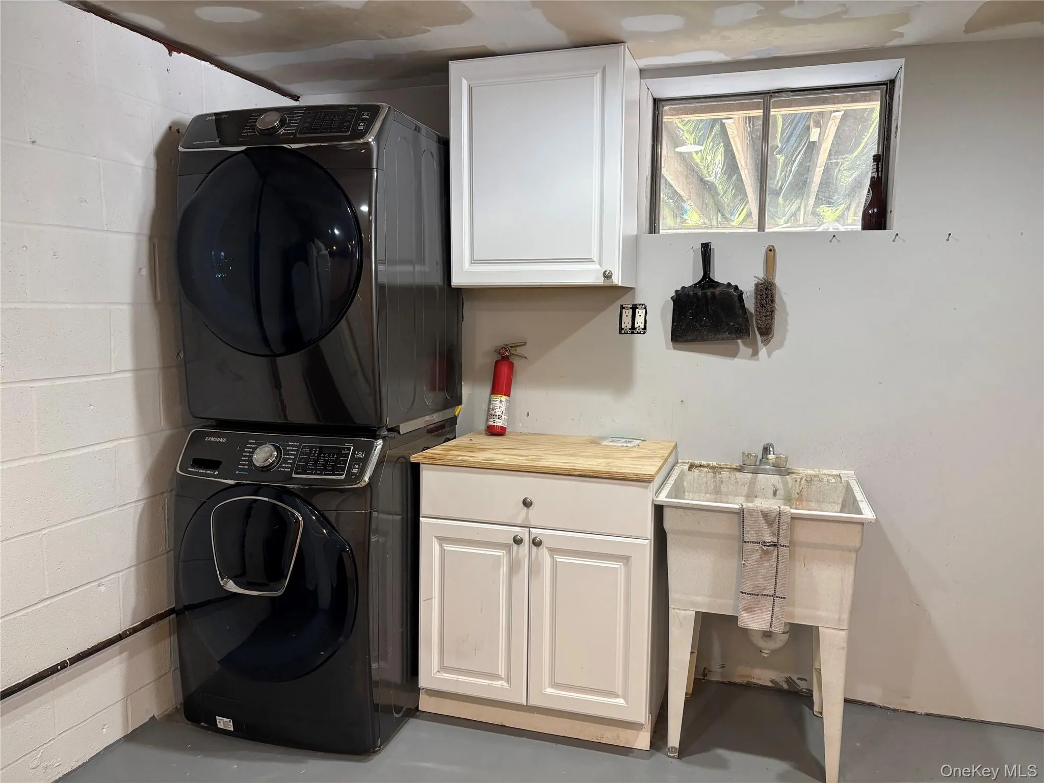 Dedicated utility area featuring a window, painted cinder block walls, and a utility sink Dedicated utility area featuring a window, painted cinder block walls, and a utility sink