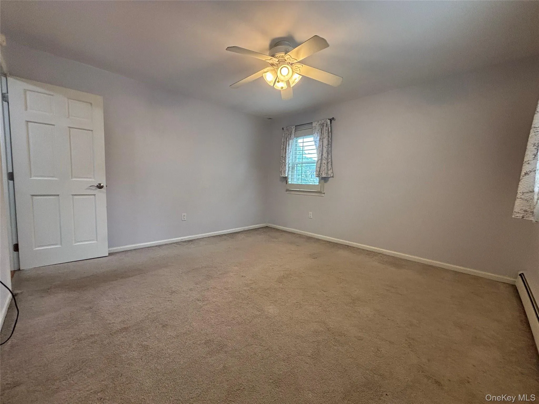 Carpeted room featuring a ceiling fan with integrated lighting, a paneled door, and a window with blinds Carpeted room featuring a ceiling fan with integrated lighting, a paneled door, and a window with blinds