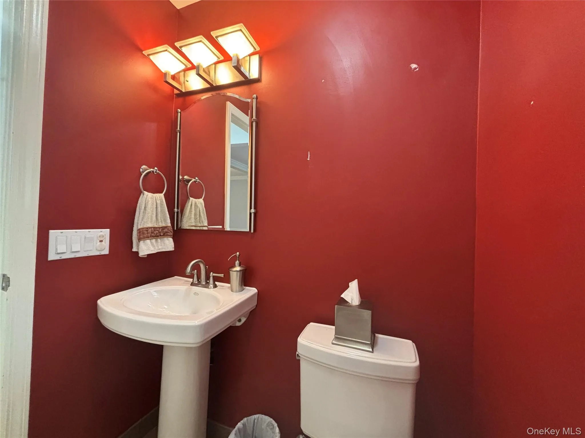 Pedestal sink with polished chrome faucet and coordinating mirror, illuminated by a contemporary vanity light fixture Pedestal sink with polished chrome faucet and coordinating mirror, illuminated by a contemporary vanity light fixture