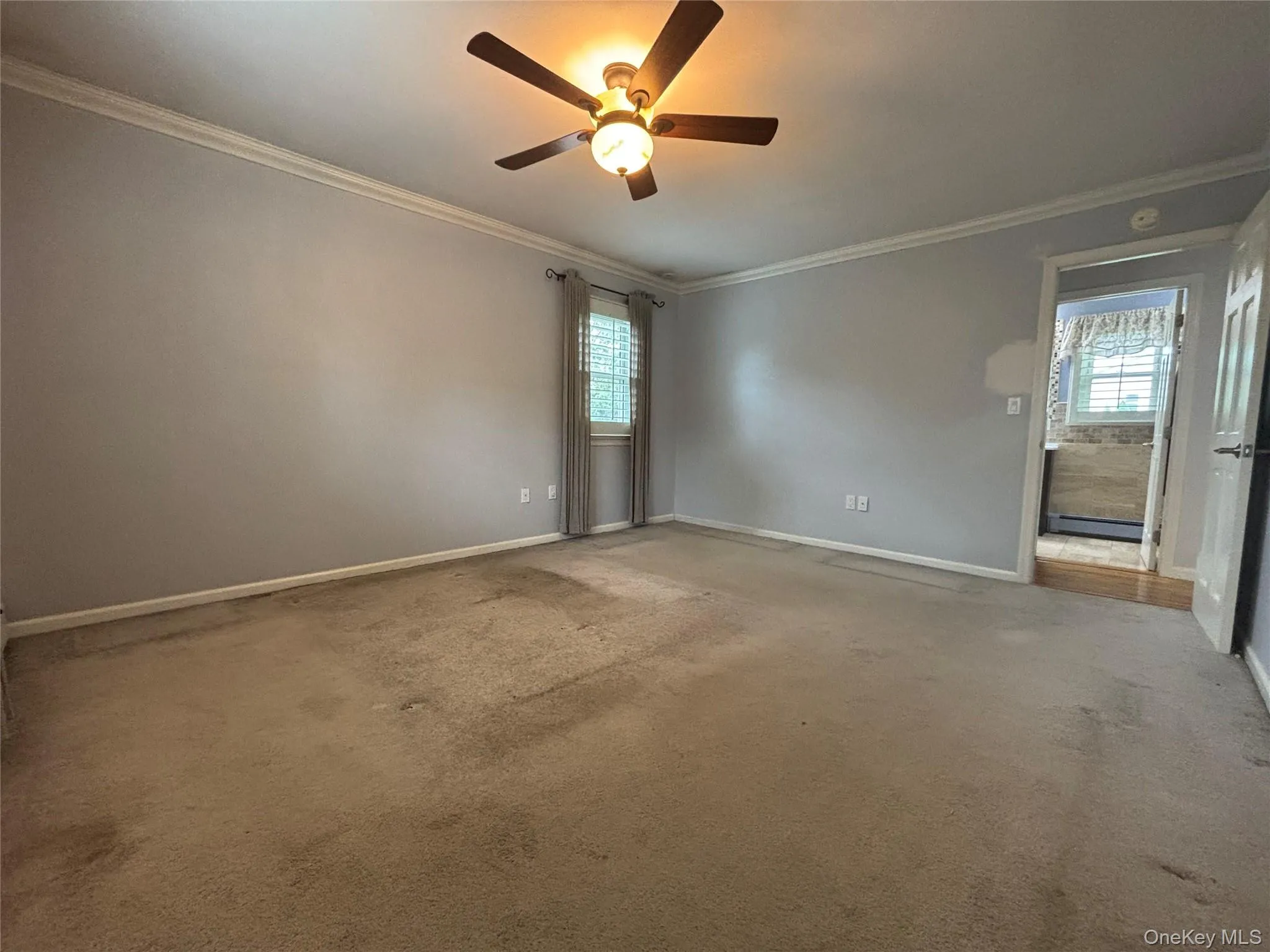 Spacious interior room featuring crown molding, neutral wall color, and a ceiling fan with integrated lighting Spacious interior room featuring crown molding, neutral wall color, and a ceiling fan with integrated lighting