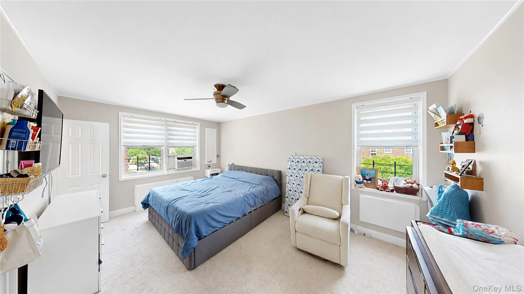 Carpeted room featuring two windows with horizontal blinds, a ceiling fan, and light gray wall paint Carpeted room featuring two windows with horizontal blinds, a ceiling fan, and light gray wall paint