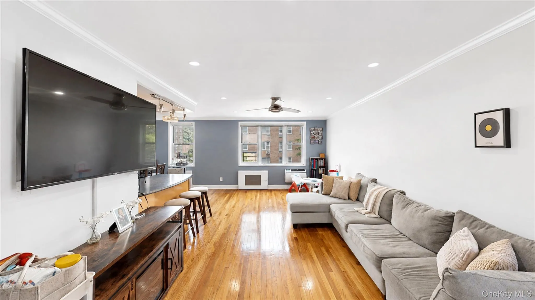 Open-concept living space featuring hardwood flooring, crown molding, recessed lighting, and a ceiling fan Open-concept living space featuring hardwood flooring, crown molding, recessed lighting, and a ceiling fan
