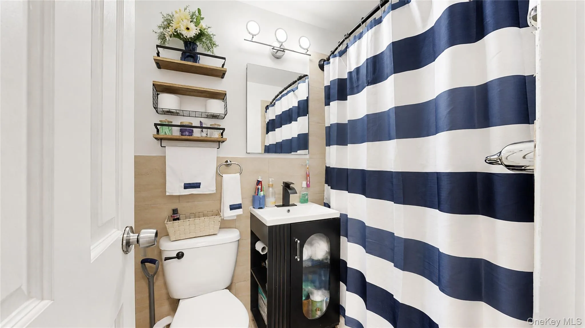 Bathroom featuring a wall-mounted vanity with a white countertop and black faucet, a toilet, and three wall-mounted shelving units Bathroom featuring a wall-mounted vanity with a white countertop and black faucet, a toilet, and three wall-mounted shelving units