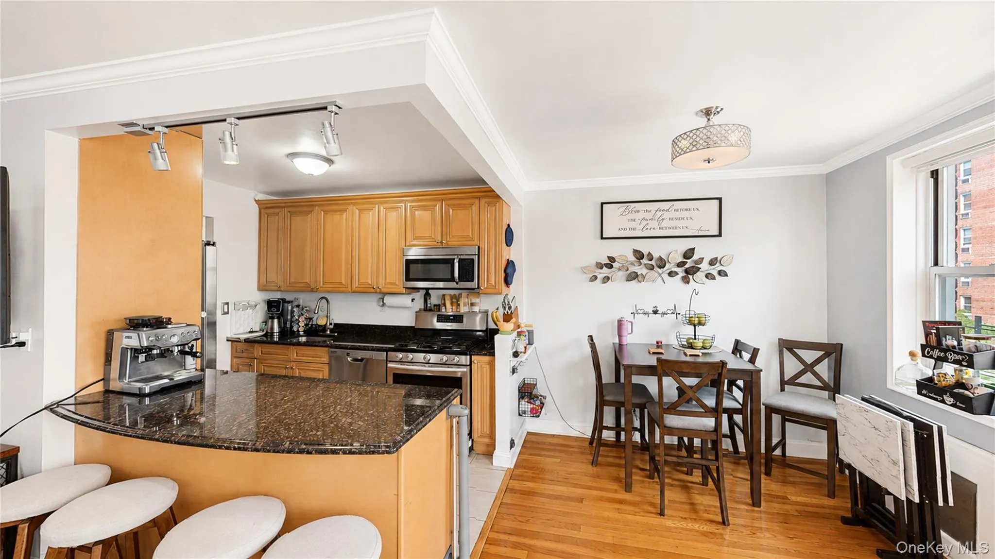 Open-concept kitchen and dining area featuring wood-finish flooring, a breakfast bar with a granite-style countertop, recessed lighting, and a stainless steel appliance suite Open-concept kitchen and dining area featuring wood-finish flooring, a breakfast bar with a granite-style countertop, recessed lighting, and a stainless steel appliance suite