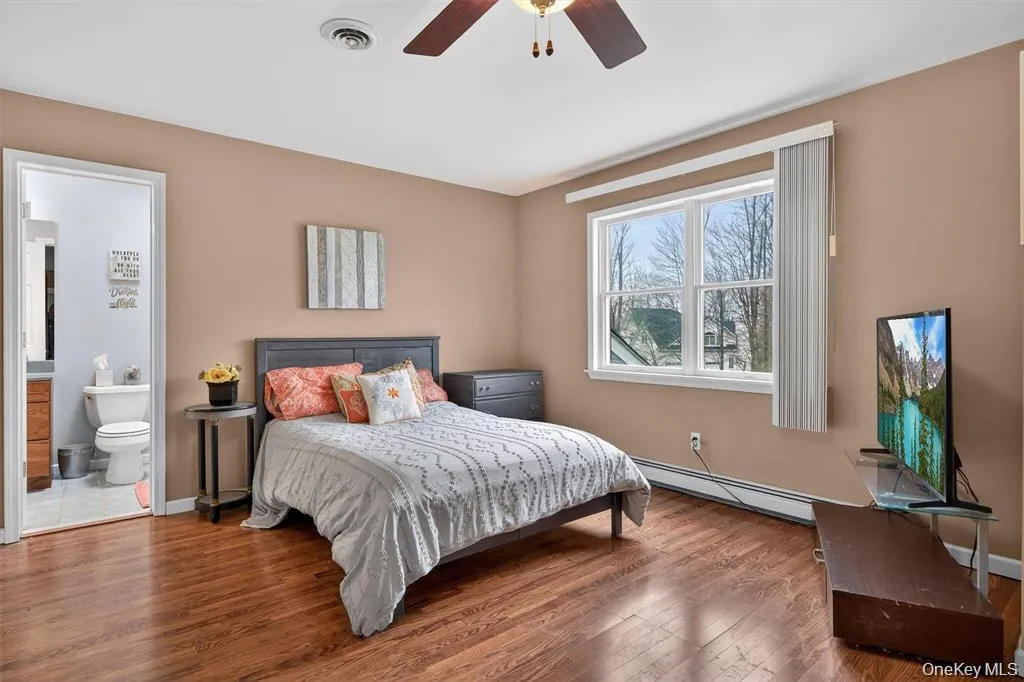 Bedroom featuring wood-finish flooring and a ceiling fan with ensuite Bedroom featuring wood-finish flooring and a ceiling fan with ensuite