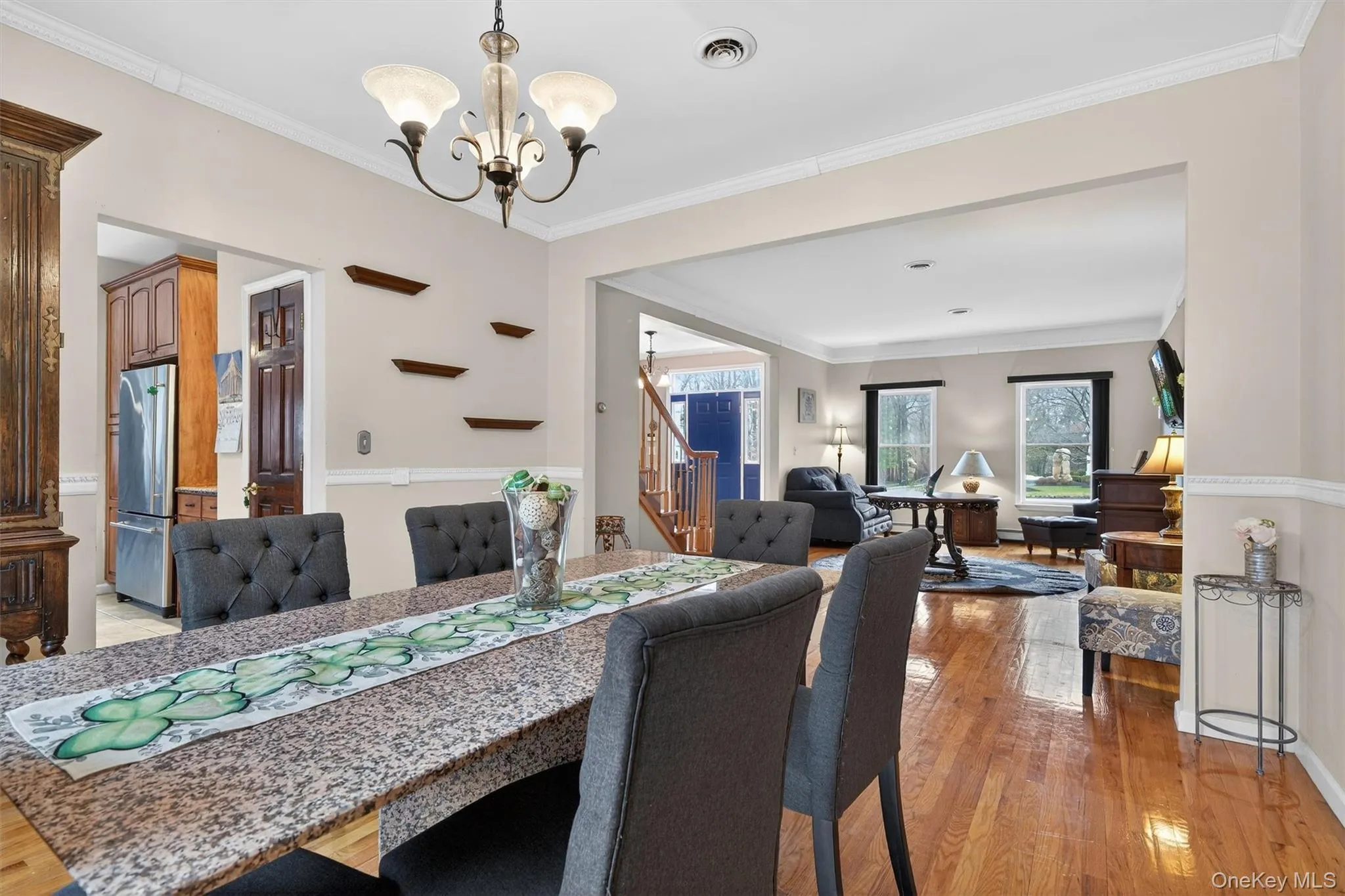 Dining area featuring a granite-top table, hardwood flooring, crown molding, and an overhead chandelier Dining area featuring a granite-top table, hardwood flooring, crown molding, and an overhead chandelier