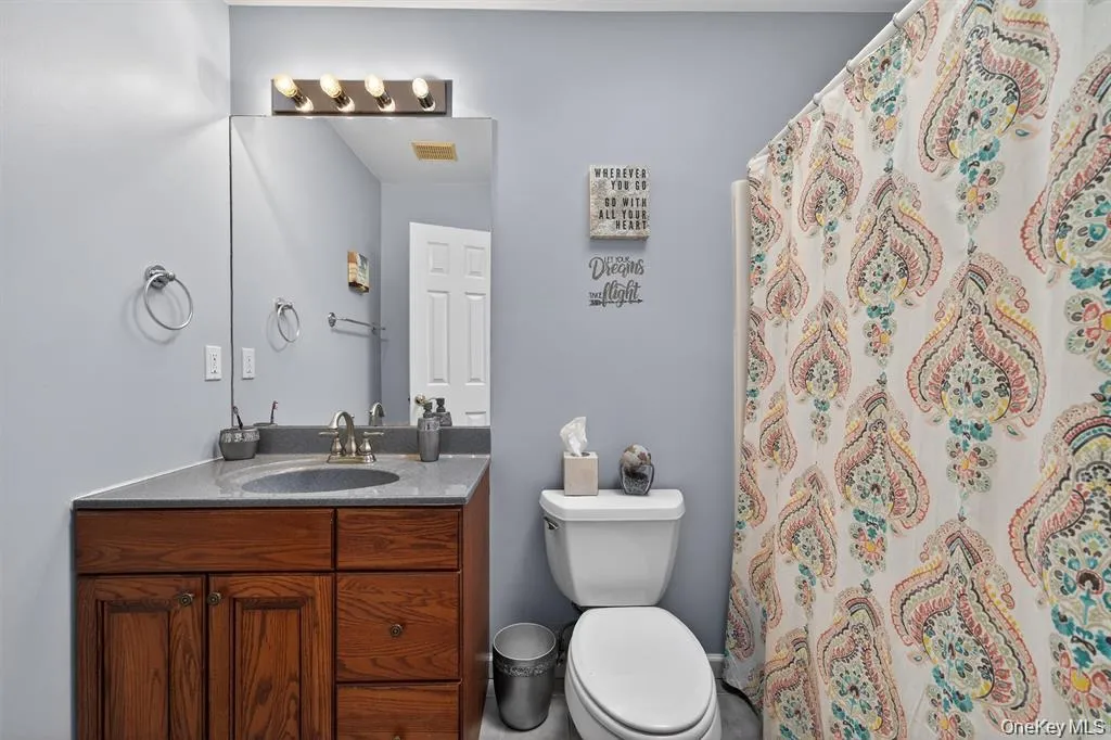 Bathroom featuring a dark wood vanity with a light-toned countertop, an undermount sink, and a mirrored wall in Guest Room Bathroom featuring a dark wood vanity with a light-toned countertop, an undermount sink, and a mirrored wall in Guest Room