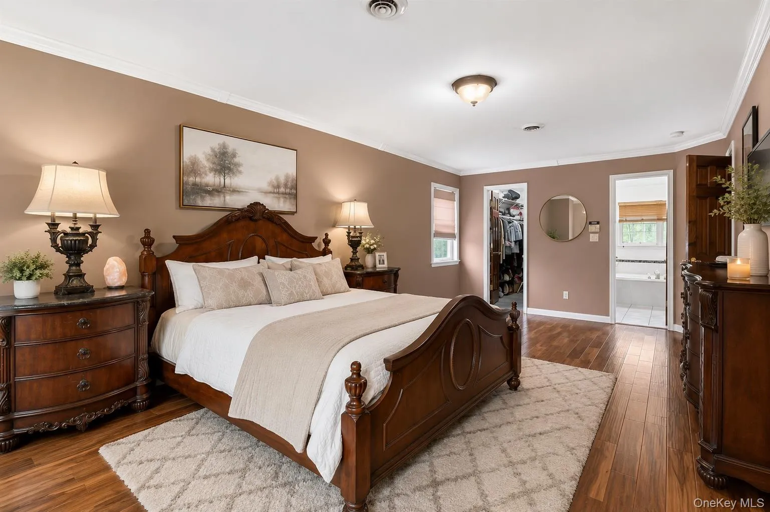 Spacious bedroom featuring wood-finish flooring, crown molding, and neutral-toned walls Spacious bedroom featuring wood-finish flooring, crown molding, and neutral-toned walls
