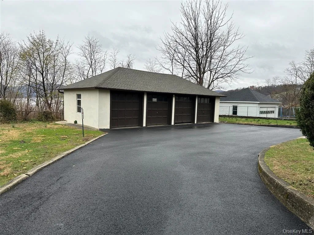 Four-car garage structure with a shingled roof and stucco exterior Four-car garage structure with a shingled roof and stucco exterior