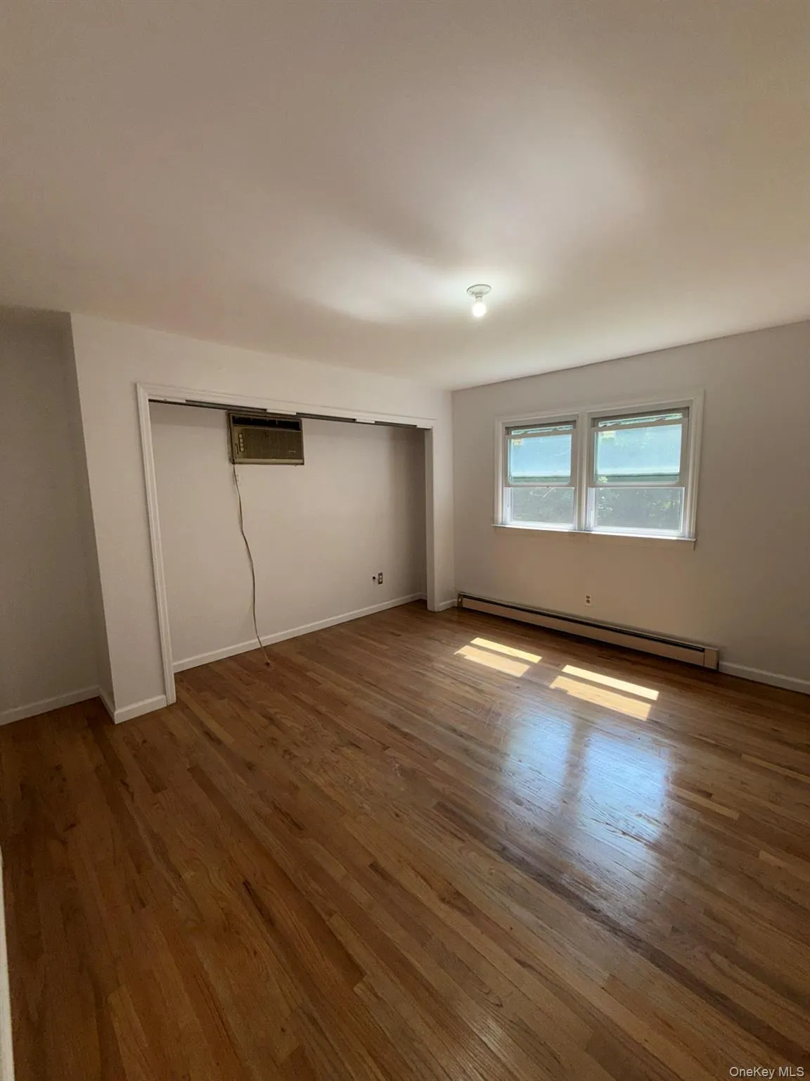 The spacious primary bedroom features an oversized closet, providing plenty of storage space. A recessed wall-unit air conditioner offers convenient cooling and comfort during warmer months. The spacious primary bedroom features an oversized closet, providing plenty of storage space. A recessed wall-unit air conditioner offers convenient cooling and comfort during warmer months.