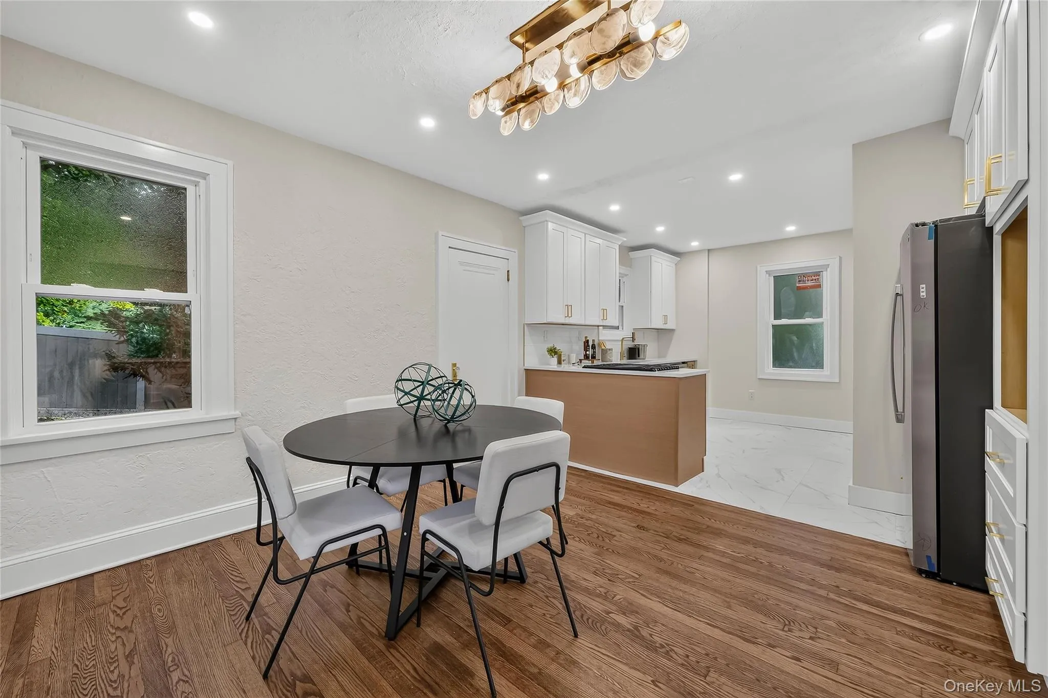 Open-concept dining area featuring wood-finish flooring, a contemporary chandelier, and recessed lighting Open-concept dining area featuring wood-finish flooring, a contemporary chandelier, and recessed lighting