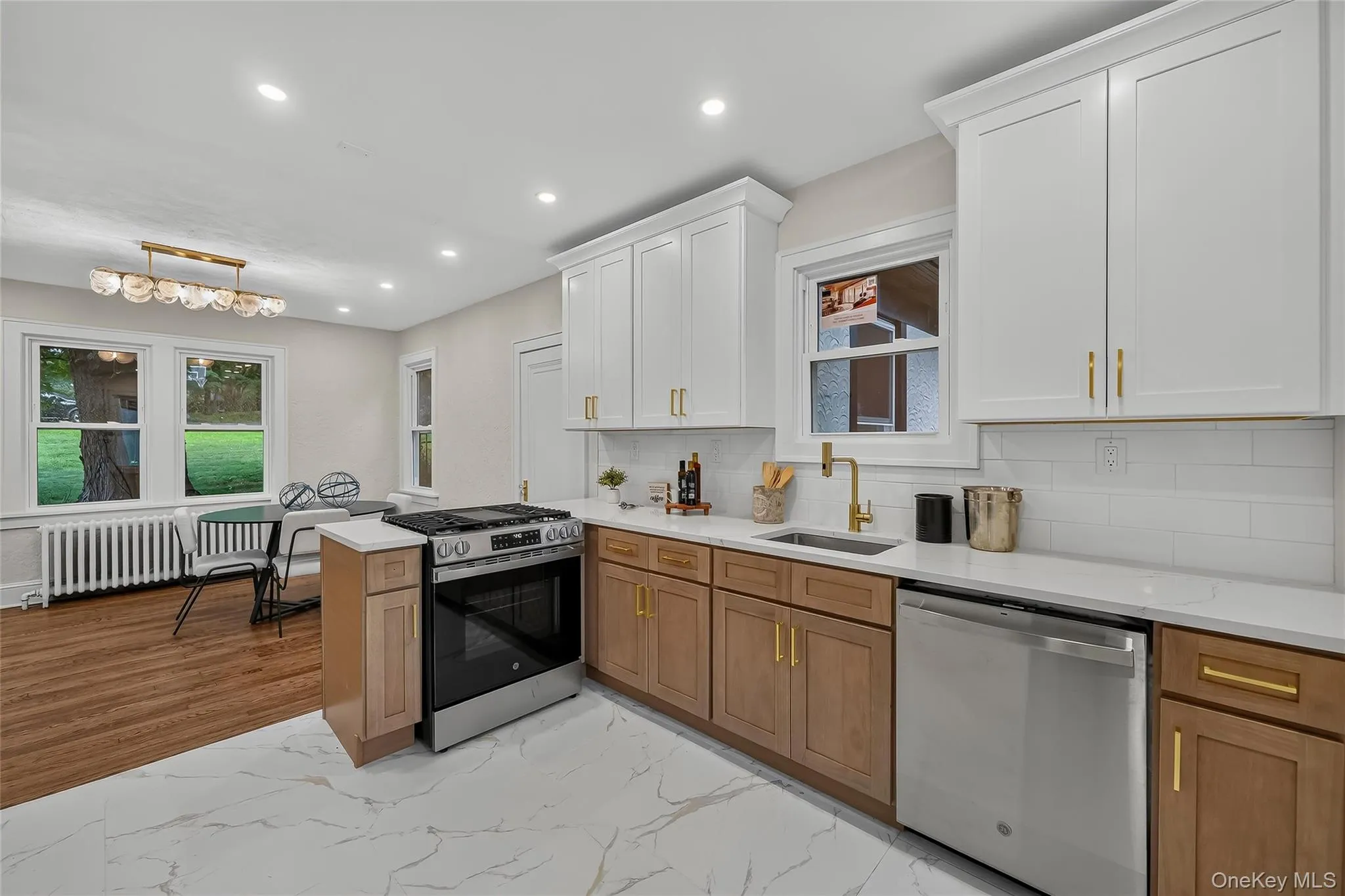 Contemporary kitchen featuring white shaker upper cabinetry and wood-finish lower cabinetry with gold-tone hardware Contemporary kitchen featuring white shaker upper cabinetry and wood-finish lower cabinetry with gold-tone hardware