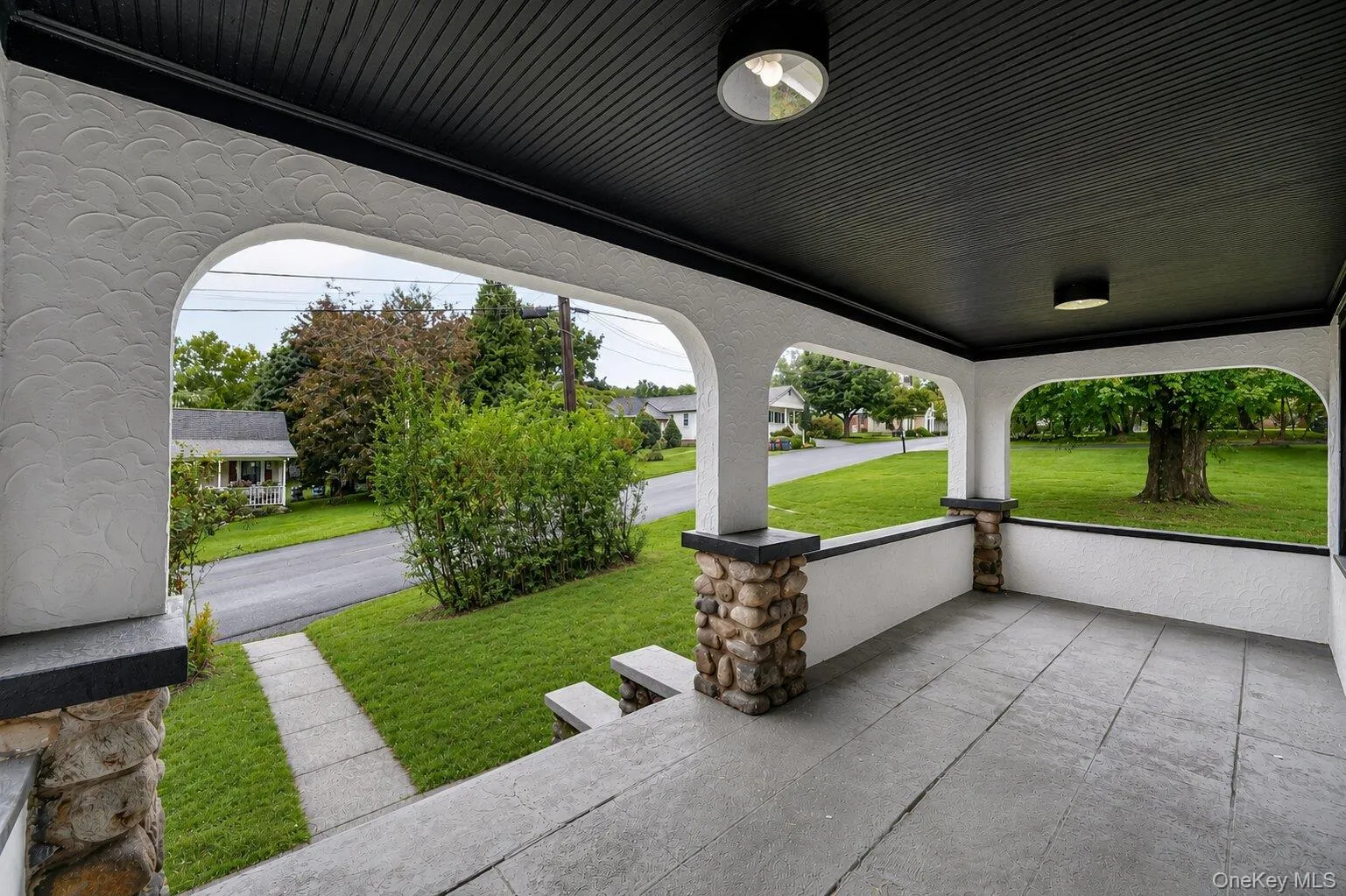 Inviting covered porch with a textured stucco finish and stone-clad pillars Inviting covered porch with a textured stucco finish and stone-clad pillars