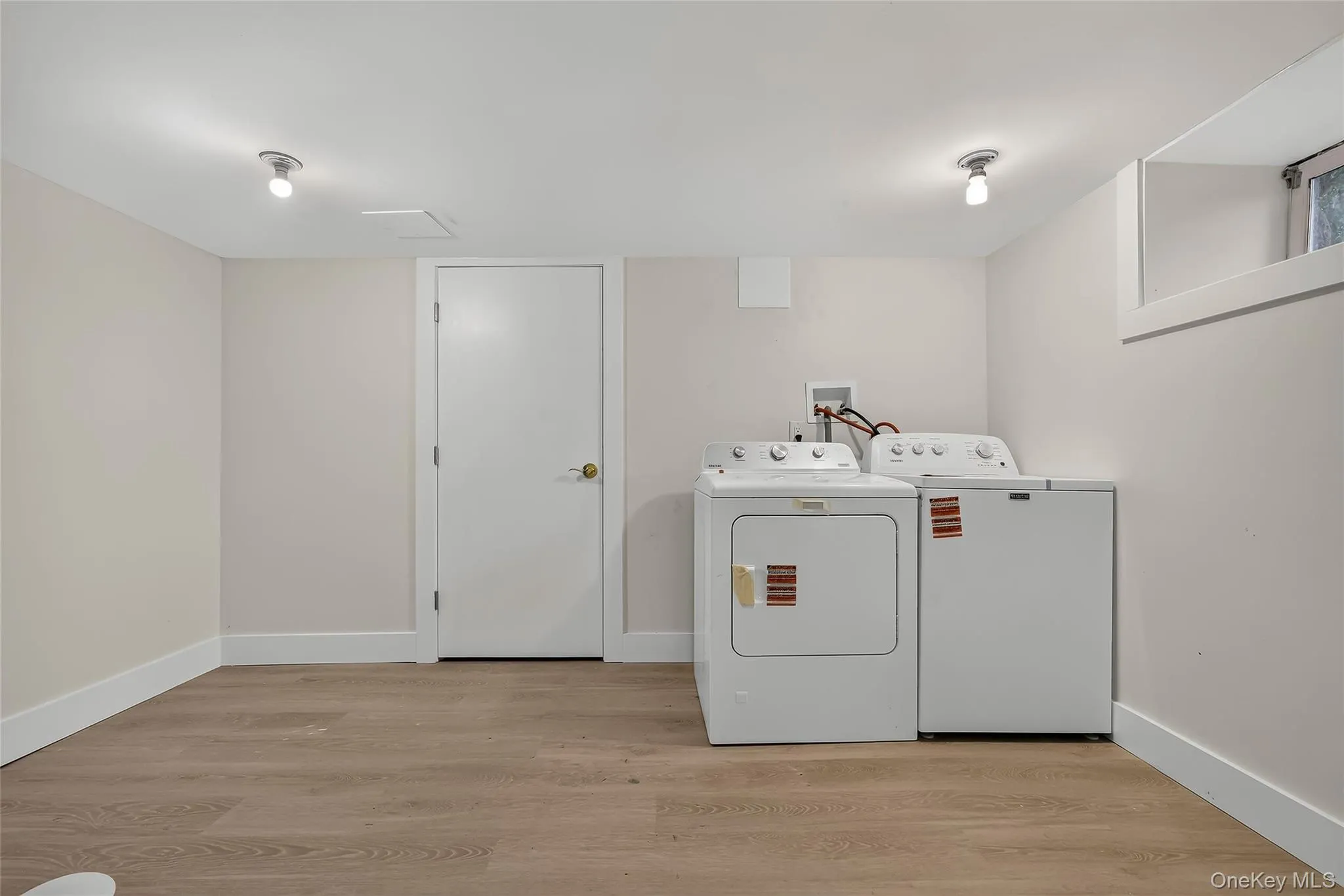 Dedicated laundry area featuring a washer and dryer, wood-finish flooring, and a window for natural light Dedicated laundry area featuring a washer and dryer, wood-finish flooring, and a window for natural light