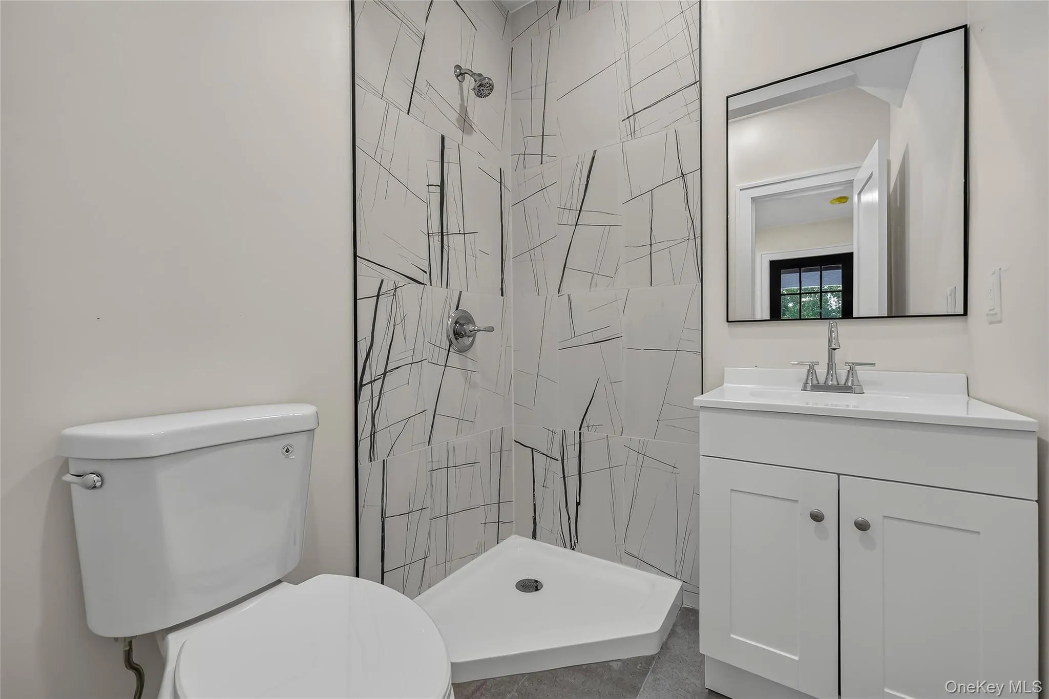 Modern bathroom featuring a corner shower with abstract tilework, a white shower pan, and chrome fixtures Modern bathroom featuring a corner shower with abstract tilework, a white shower pan, and chrome fixtures